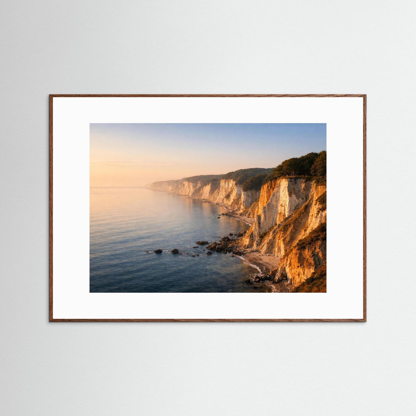 Wandbild mit hellbraunem Holzrahmen: Steilküste und Meer bei Sonnenaufgang