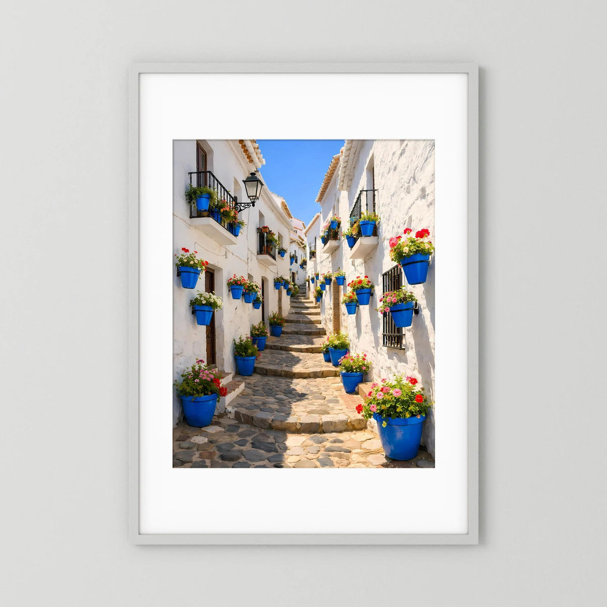 Poster mit Gassenmotiv und blauen Blumenkübeln, weißer Rahmen