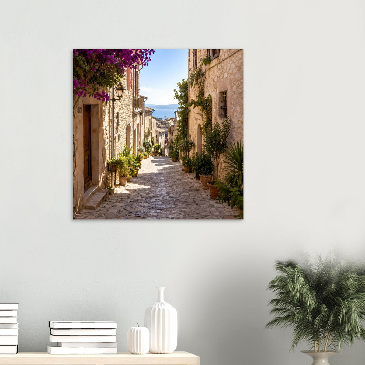 Quadratisches Wandposter mit Blick in eine mediterrane Stein-Gasse, üppige Pflanzen und lila Blüten