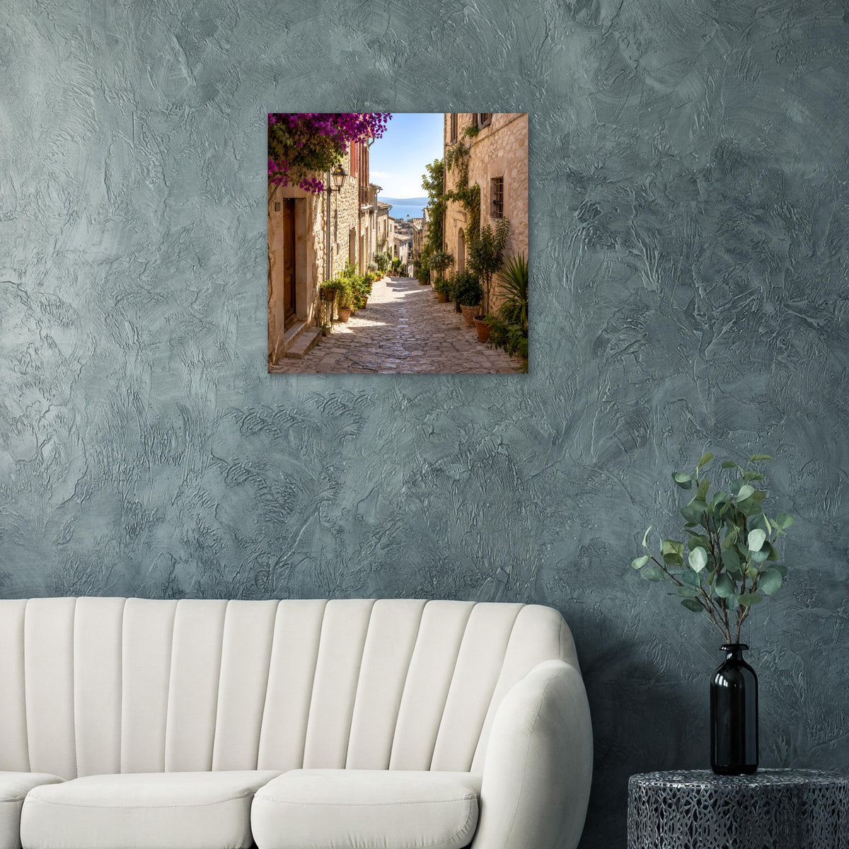 Quadratisches Poster: mediterrane Gasse zwischen Steingebäuden, lila Blüten und Grün