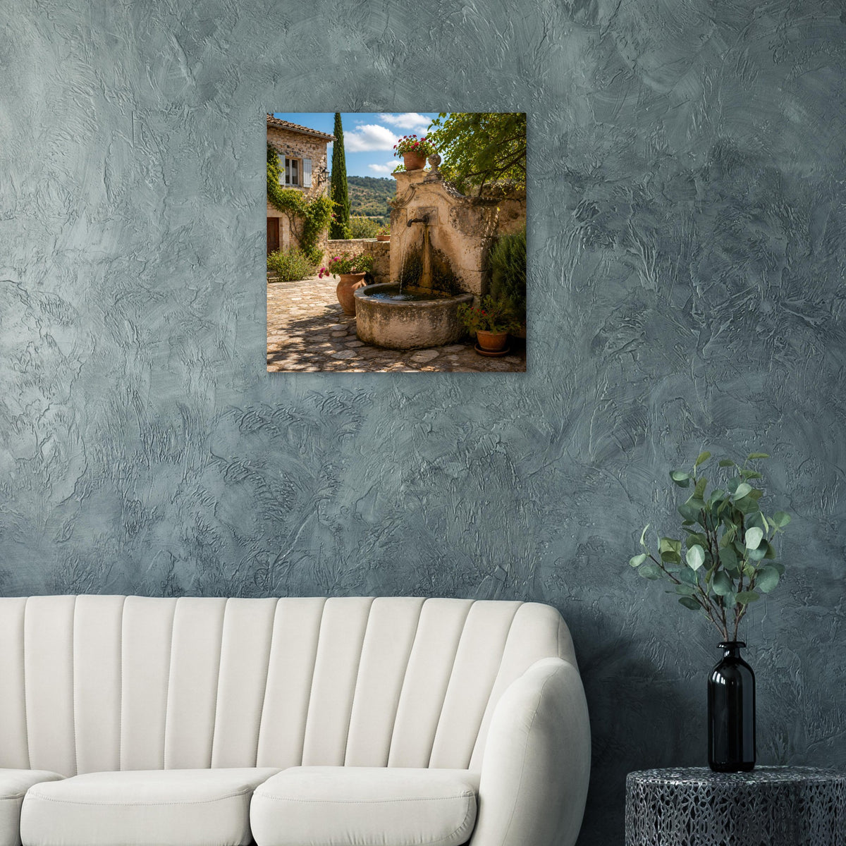 Quadratisches Poster zeigt Steinbrunnen mit Pflanzenkübeln und mediterranem Innenhofweg