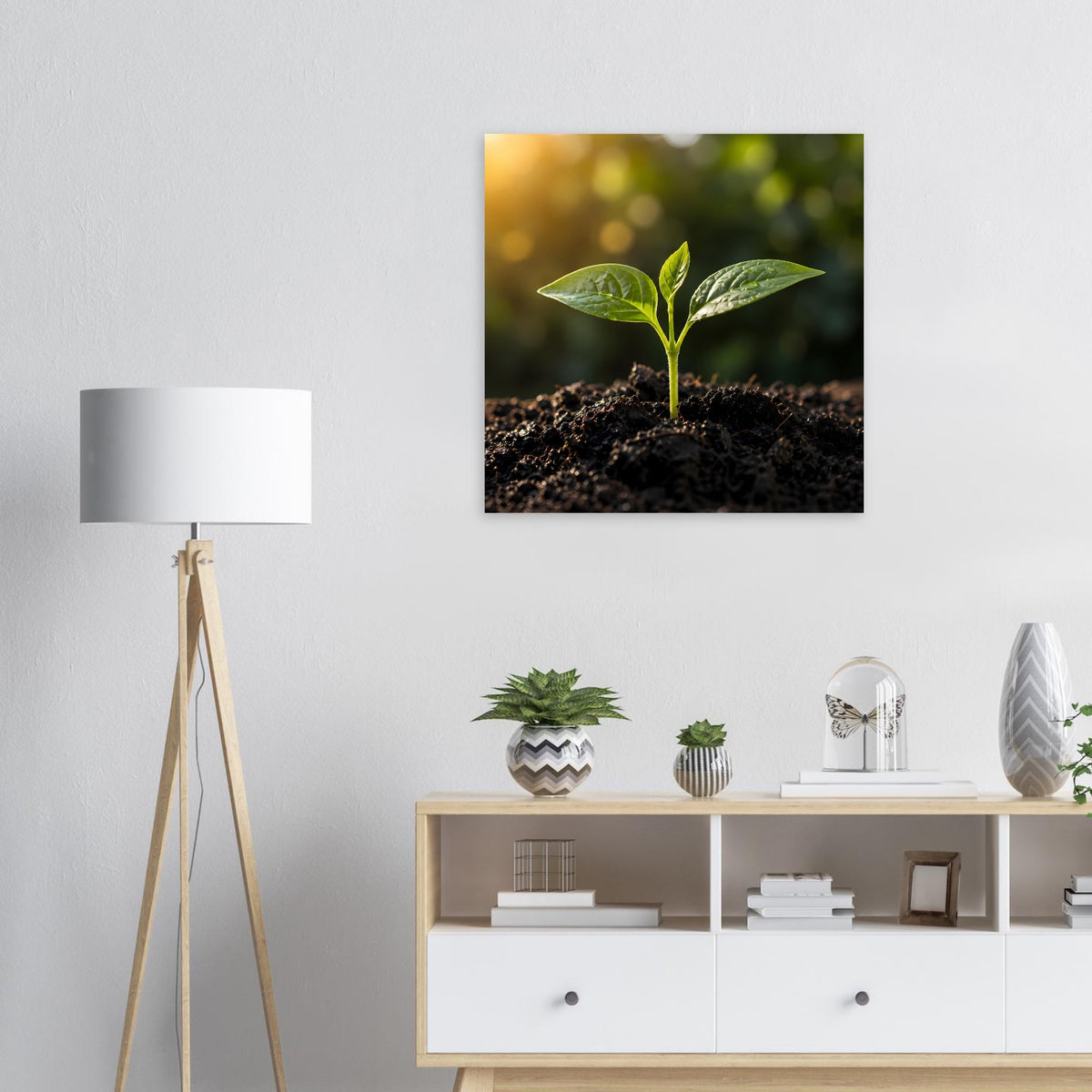 Gerahmtes Natur-Wandbild mit jungem grünen Spross in dunkler Erde, mit hellen Bokeh-Akzenten