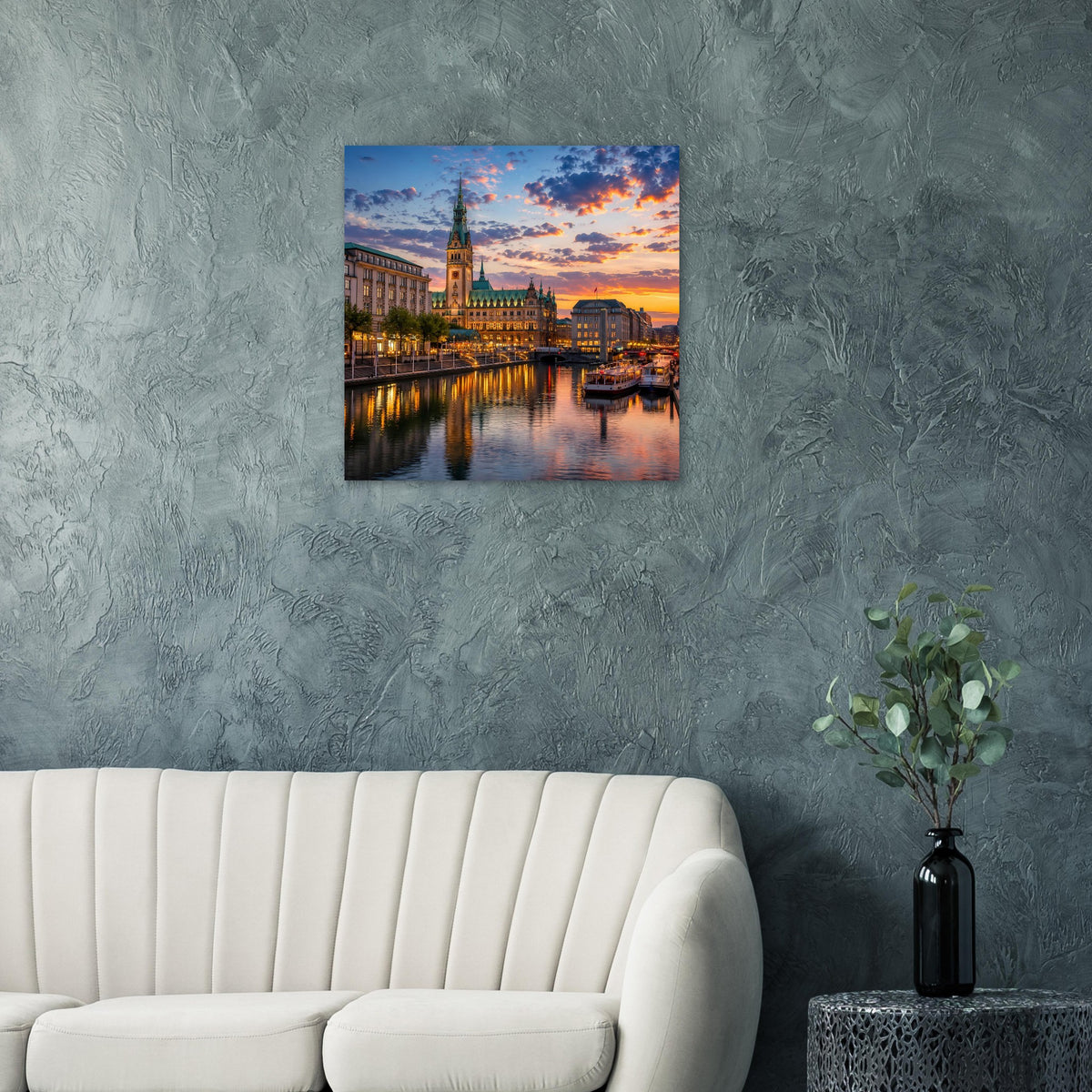 Quadratisches Wandbild an grauer Wand mit Stadtansicht bei Sonnenuntergang und spiegelndem Wasser