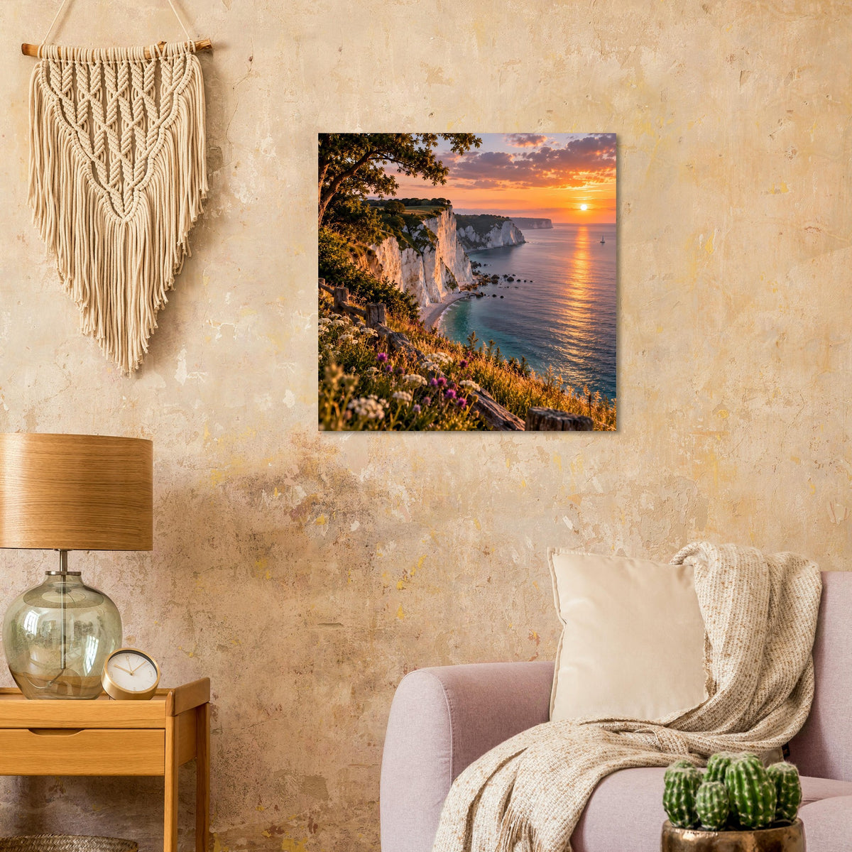 Wandposter mit Küstenklippen, blumenreicher Wiese und Sonnenuntergang über dem Meer.