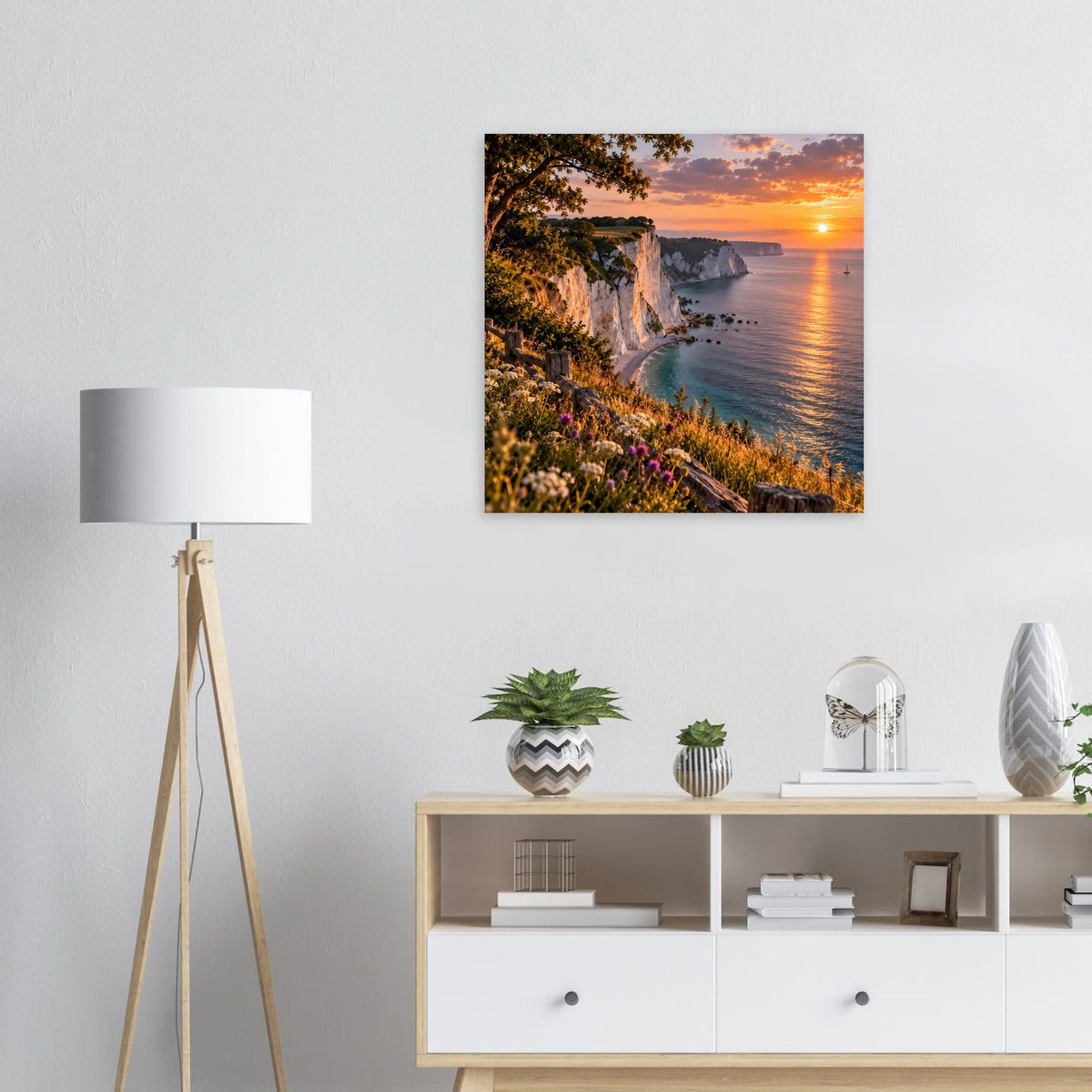 Wandposter mit Steilküste, blühendem Hang und orangefarbenem Sonnenuntergang am Meer.
