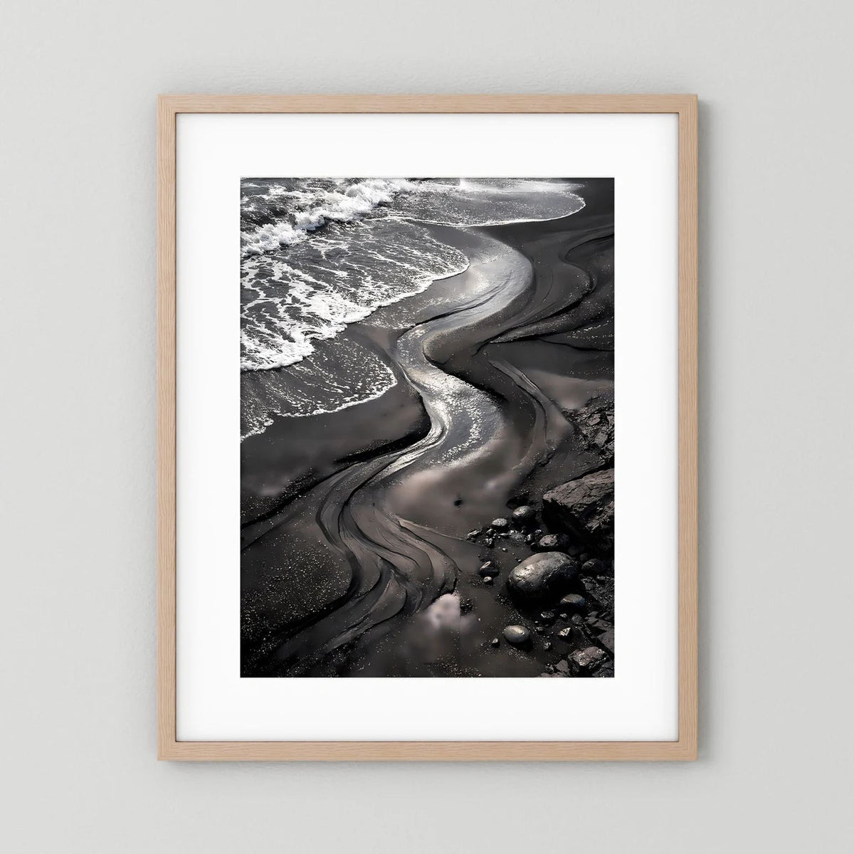 Strandposter mit schwarzem Sand und Meereswellen, beigefarbener Holzrahmen mit weißem Rand