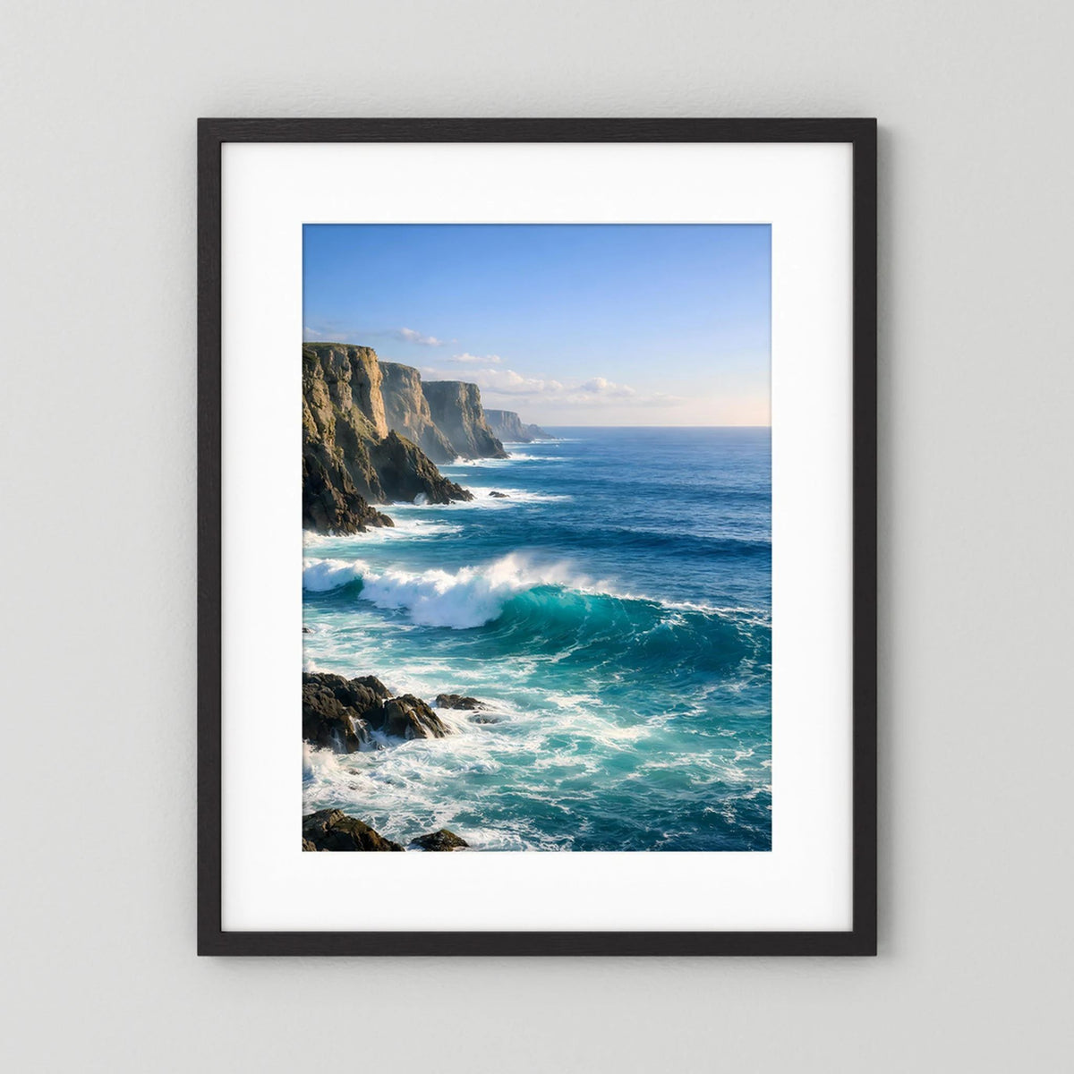 Wandbild im Hochformat mit Steilküste und tosenden Wellen, schwarzer Rahmen