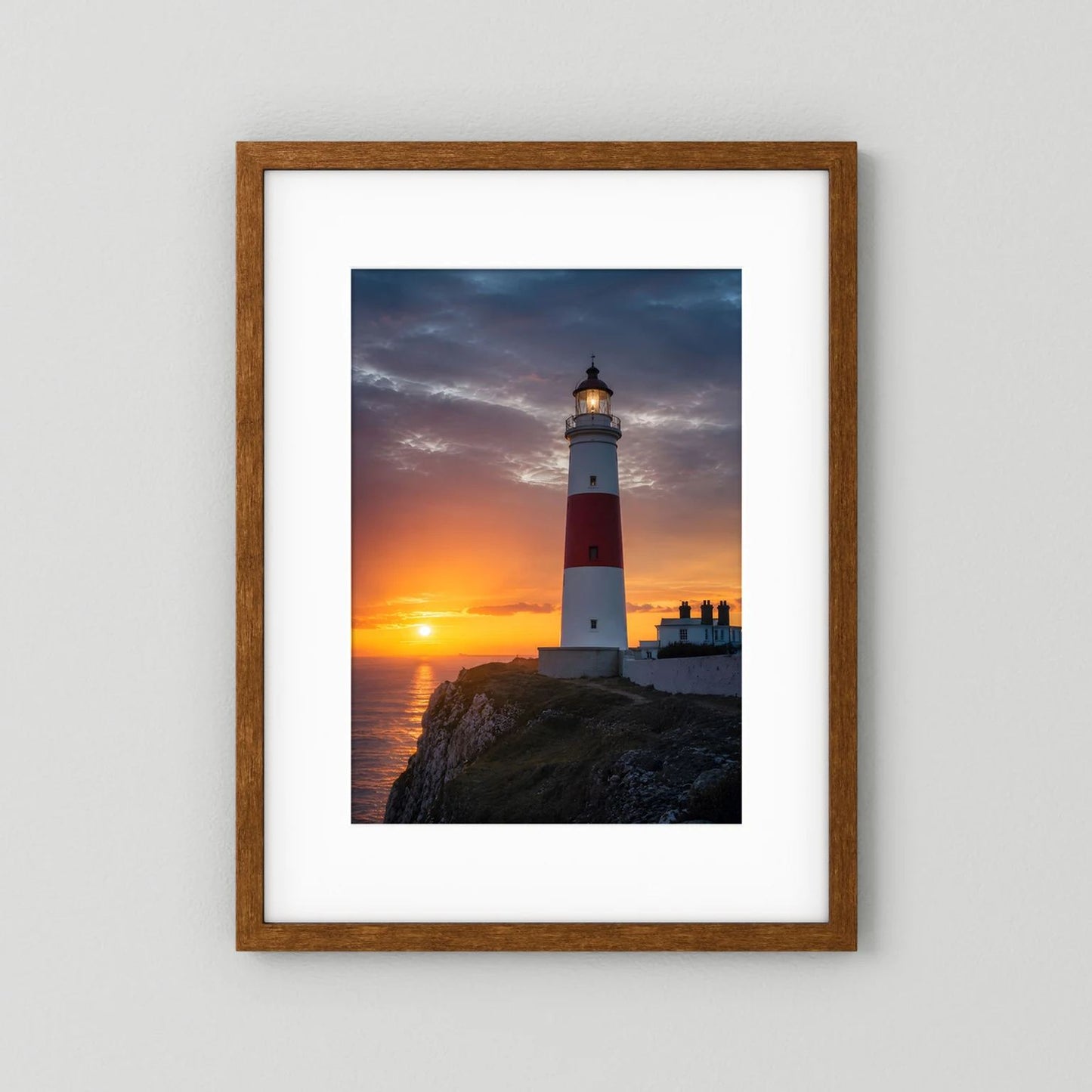 Wandposter mit Leuchtturm am Meer bei Sonnenuntergang, Eichenrahmen mit weißer Einfassung