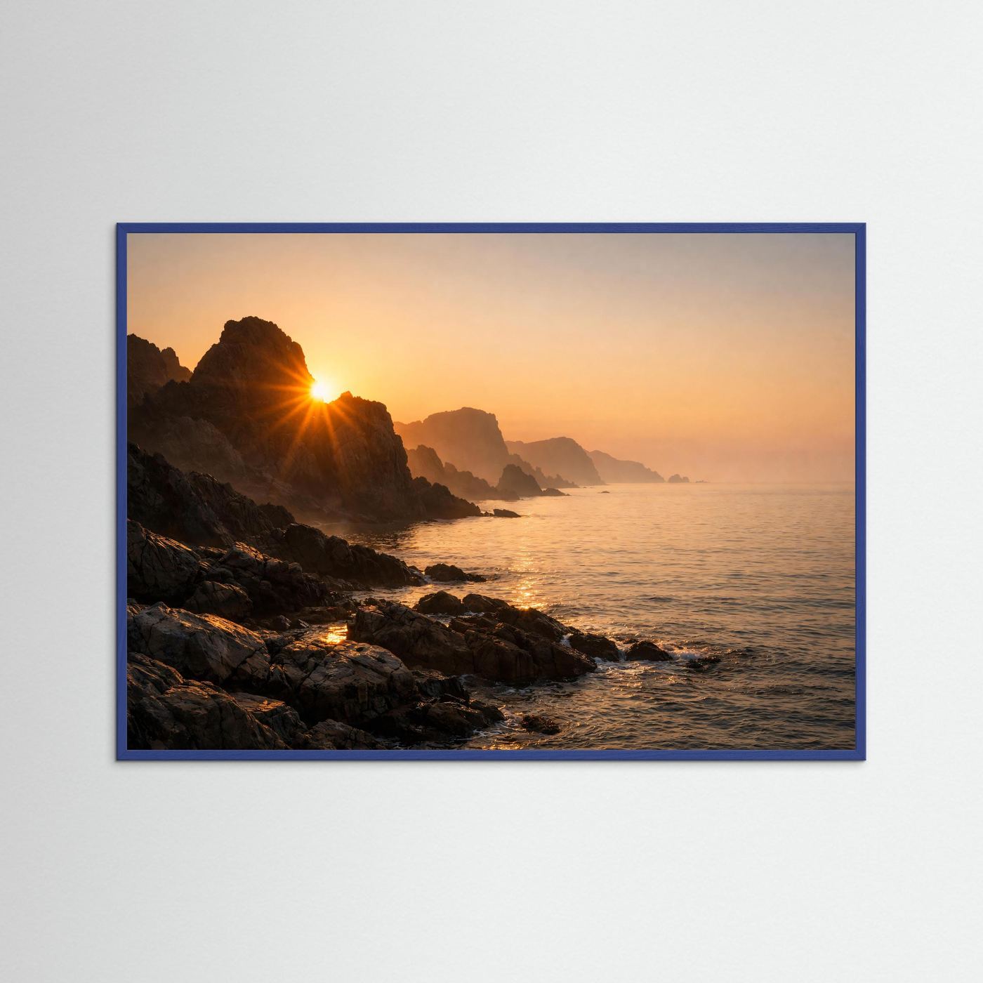 Poster im Querformat mit Sonnenaufgang an der felsigen Küste und Meer, blauer Holzrahmen