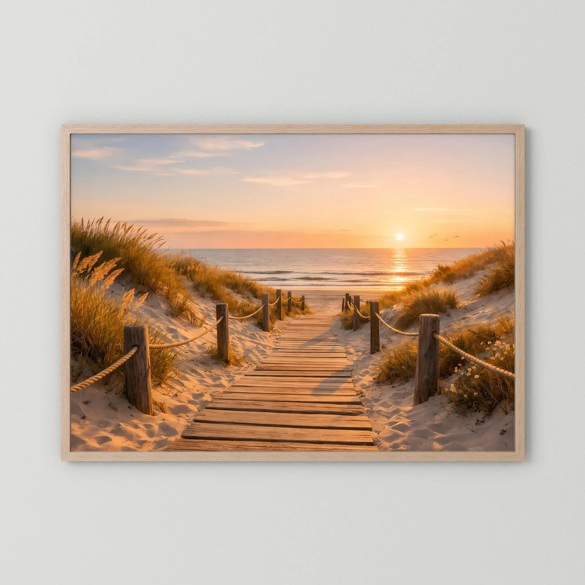 Wandbild mit hellem Holzrahmen und Dünenweg am Meer bei Sonnenuntergang