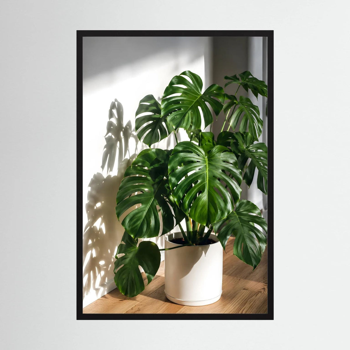 Monstera-Poster mit schwarzem Rahmen, grüne Blätter in beigem Topf