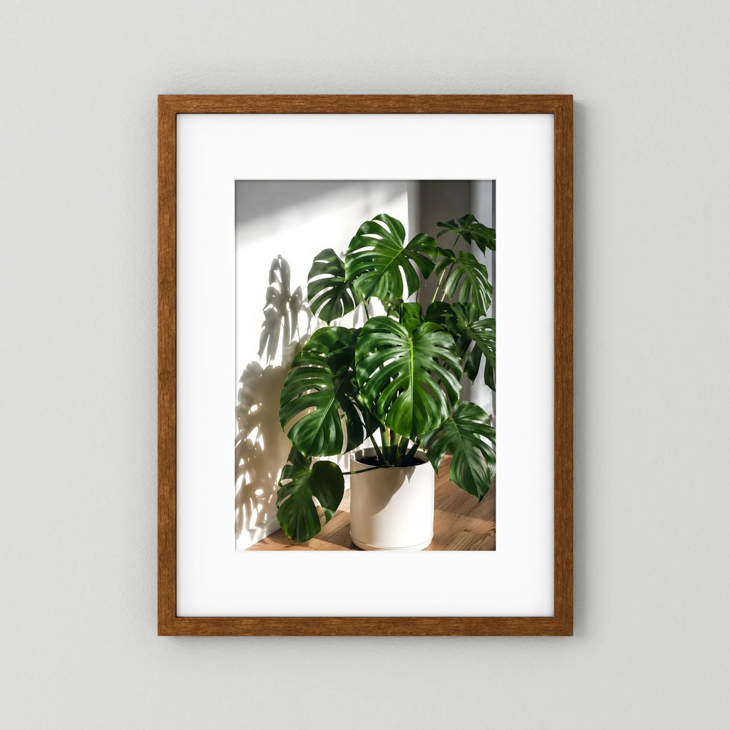 Monstera-Poster mit braunem Holzrahmen, grüne Blätter im weißen Topf