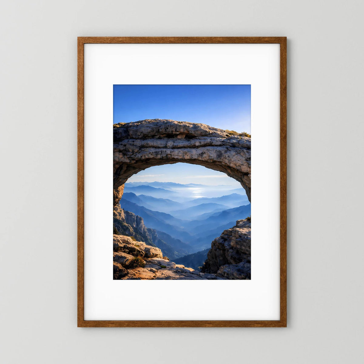 Gerahmtes Poster mit Felsbogen und Bergpanorama, dunkler Holzrahmen im Hochformat