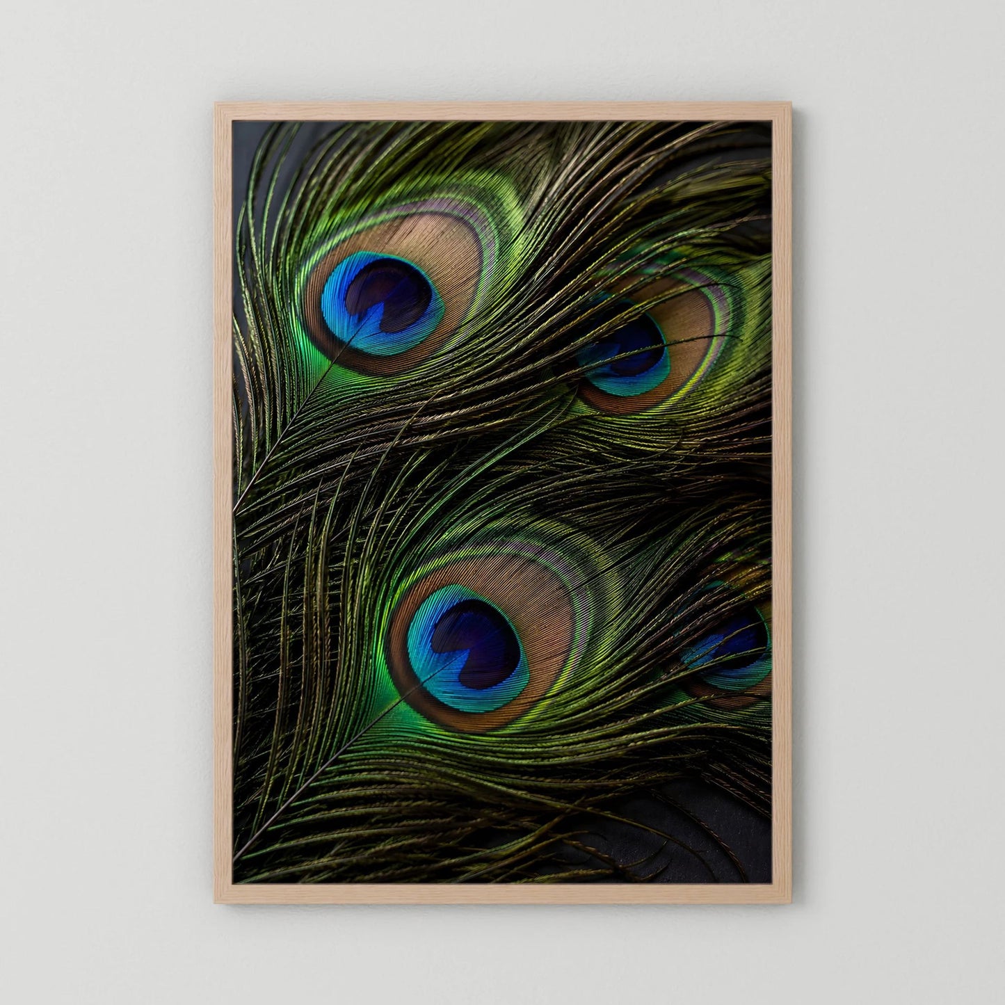 Hochformat-Poster mit Pfauenfedern: schillernde grüne Federn mit blauen Augen, Holzrahmen hell.