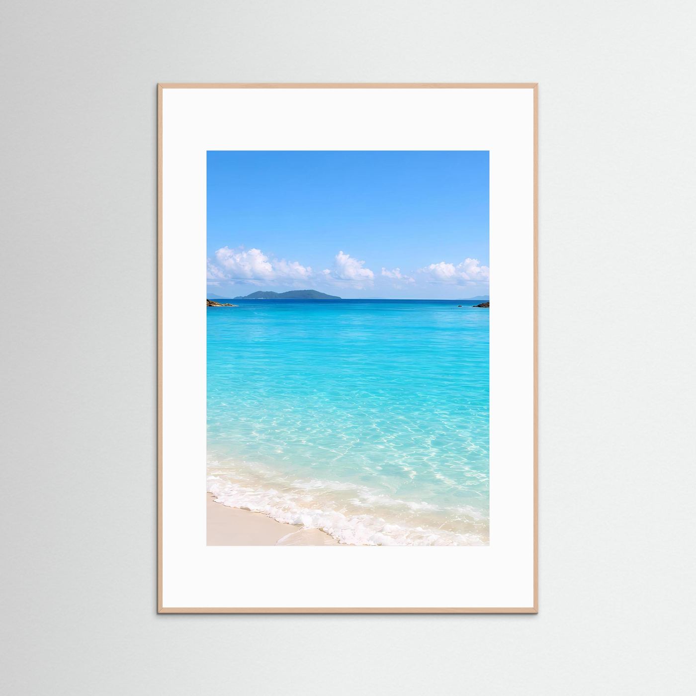 Wandbild mit hellem Holzrahmen und weißem Rand; Strand mit türkisblauem Wasser.