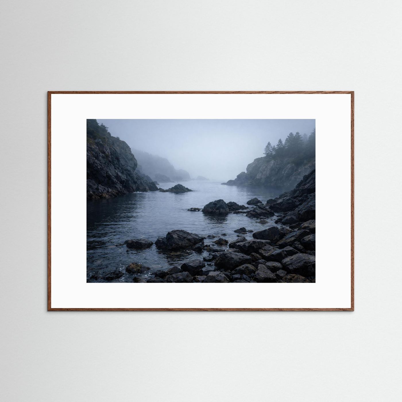 Naturposter Querformat mit braunem Holzrahmen: neblige Felsenküste am Meer, dunkle Felsen