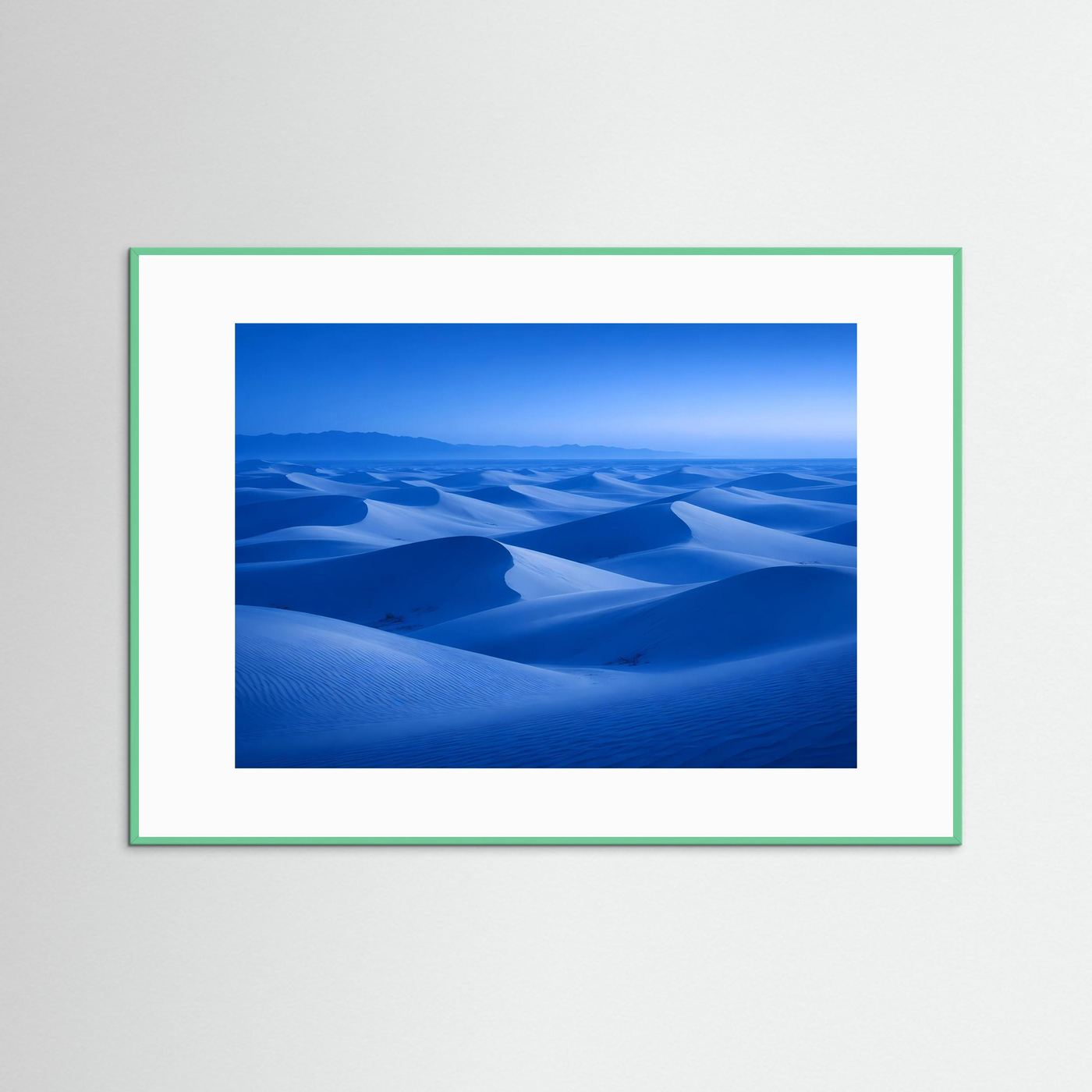 Wandbild mit blauem Dünenlandschaft-Motiv im grünlichen Rahmen mit weißem Rand