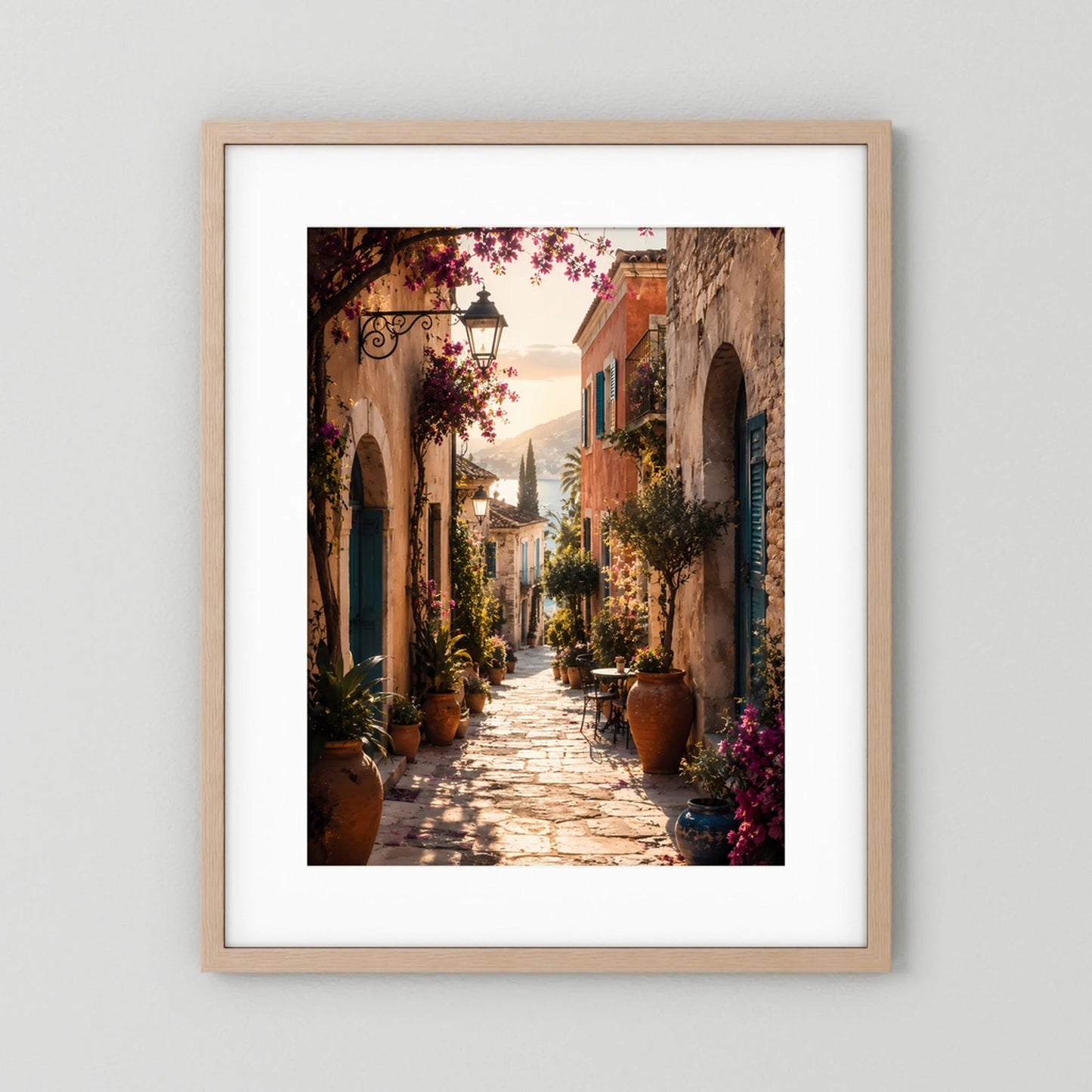 Hochformat-Poster mediterrane Gasse mit Bögen, Pflanzen und violetten Blüten im hellen Holzrahmen mit Passepartout.