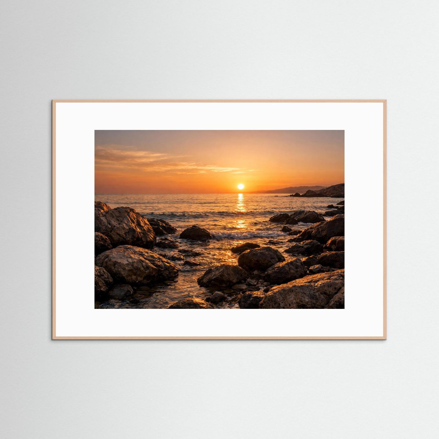 Naturposter mit Sonnenuntergang an felsiger Küste im hellen Holzrahmen