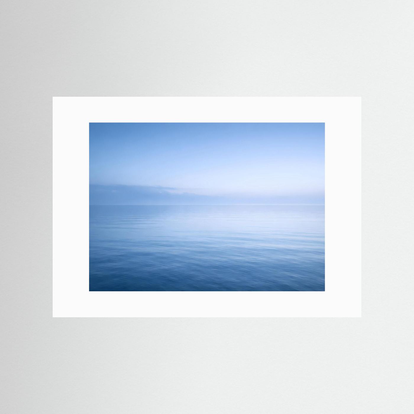 Meer-Wandbild Querformat mit weißem Passepartout, blaues Horizontmotiv über Wasser.