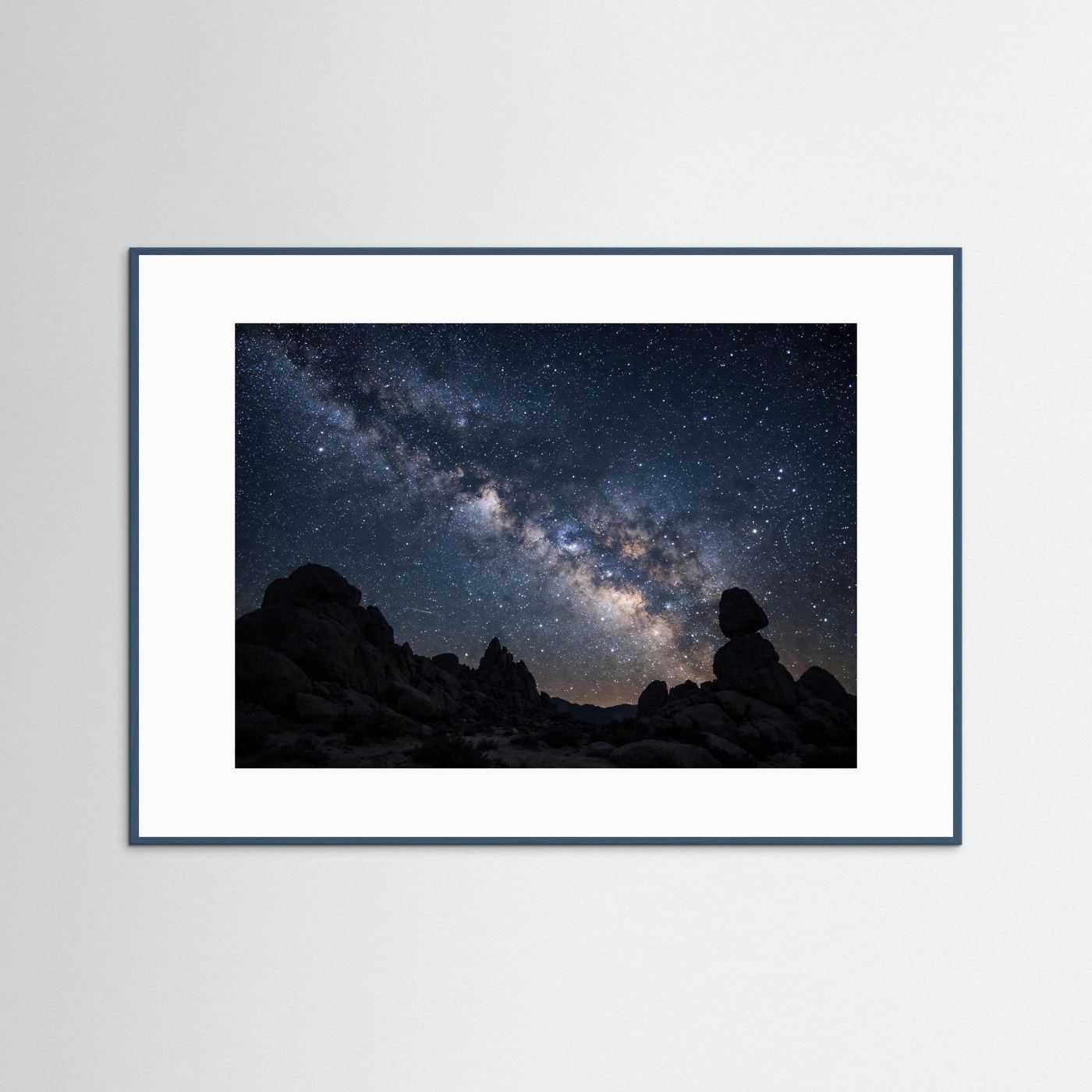 Wandbild mit dunkelblauem Holzrahmen und weißem Passepartout, Sternenhimmel über Felsen