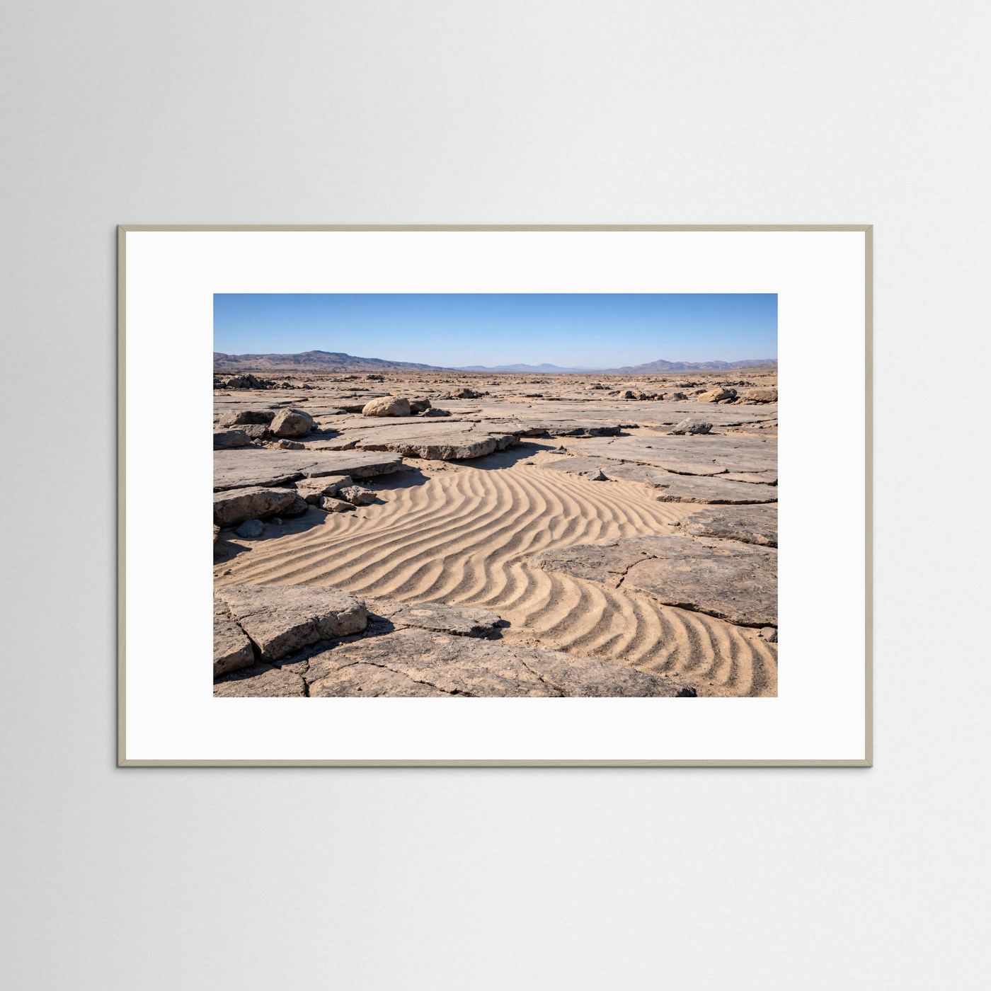Naturposter im grauen Rahmen: Sanddünen mit Felsbrocken und Bergpanorama