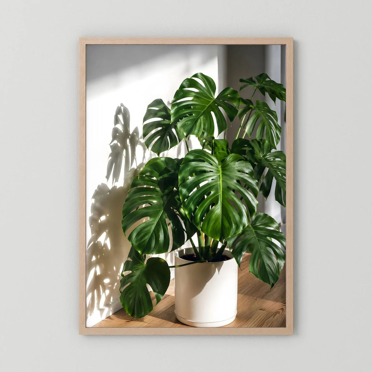 Monstera-Poster mit hellem Holzrahmen, grüne Blätter im beigen Topf