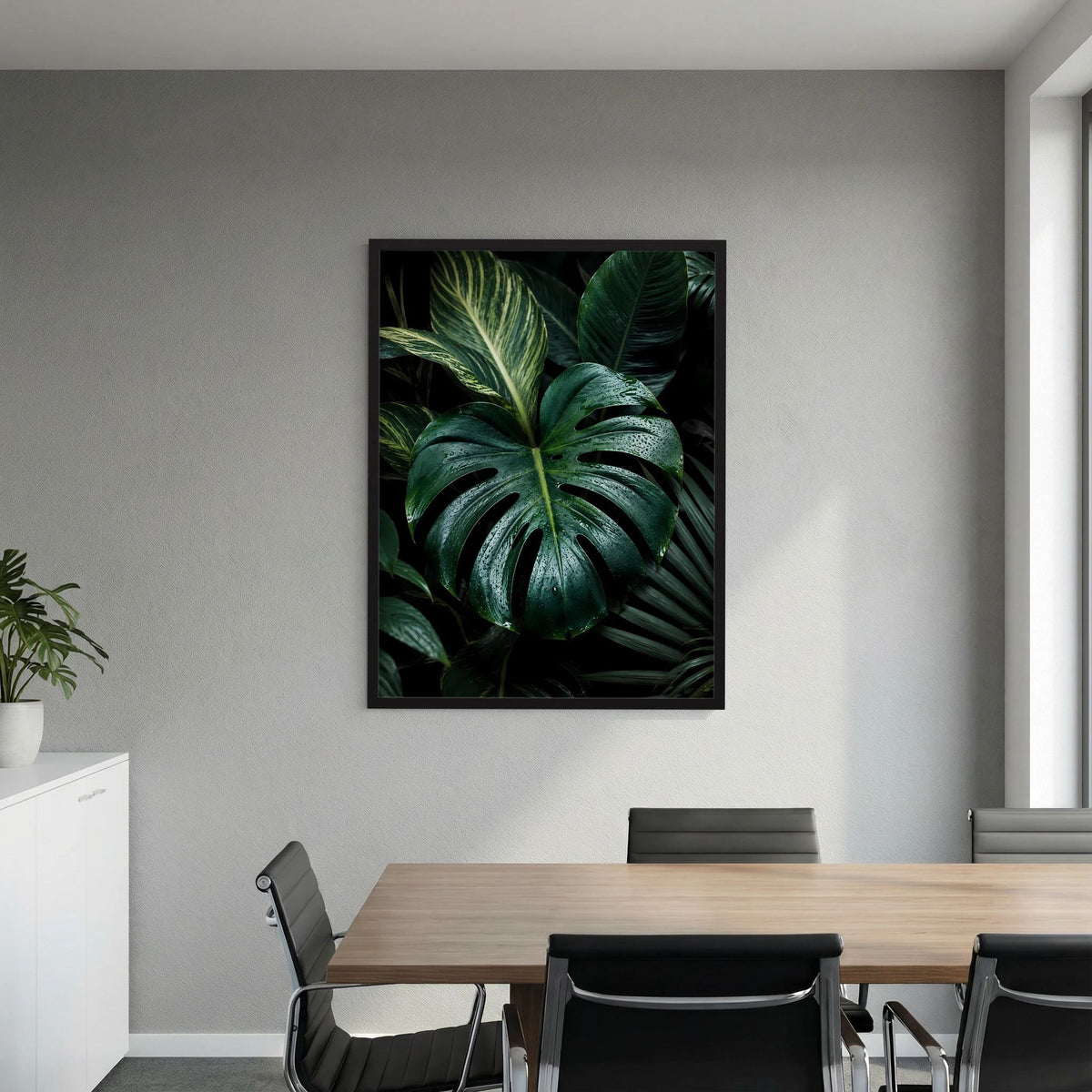 Gerahmtes, quadratisches Poster mit Monstera-Blättern in dunkelgrün, schwarzer Rahmen.