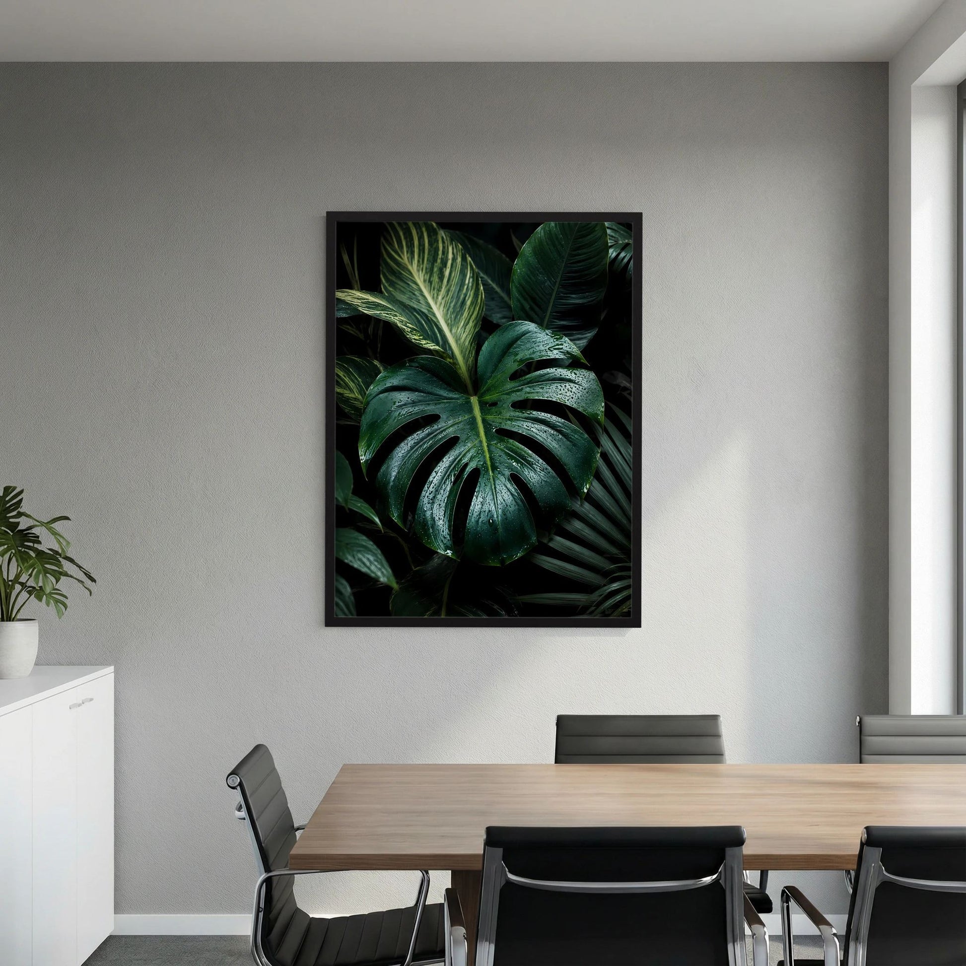 Gerahmtes, quadratisches Poster mit Monstera-Blättern in dunkelgrün, schwarzer Rahmen.