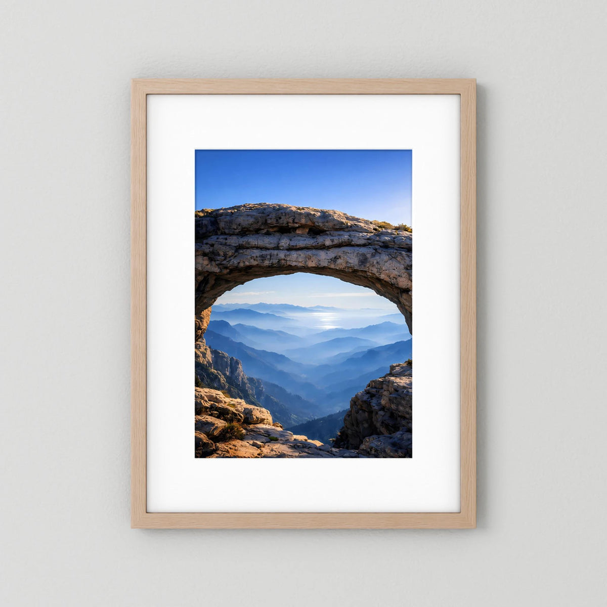 Gerahmtes Poster mit Felsbogen und Bergpanorama, heller Holzrahmen im Hochformat