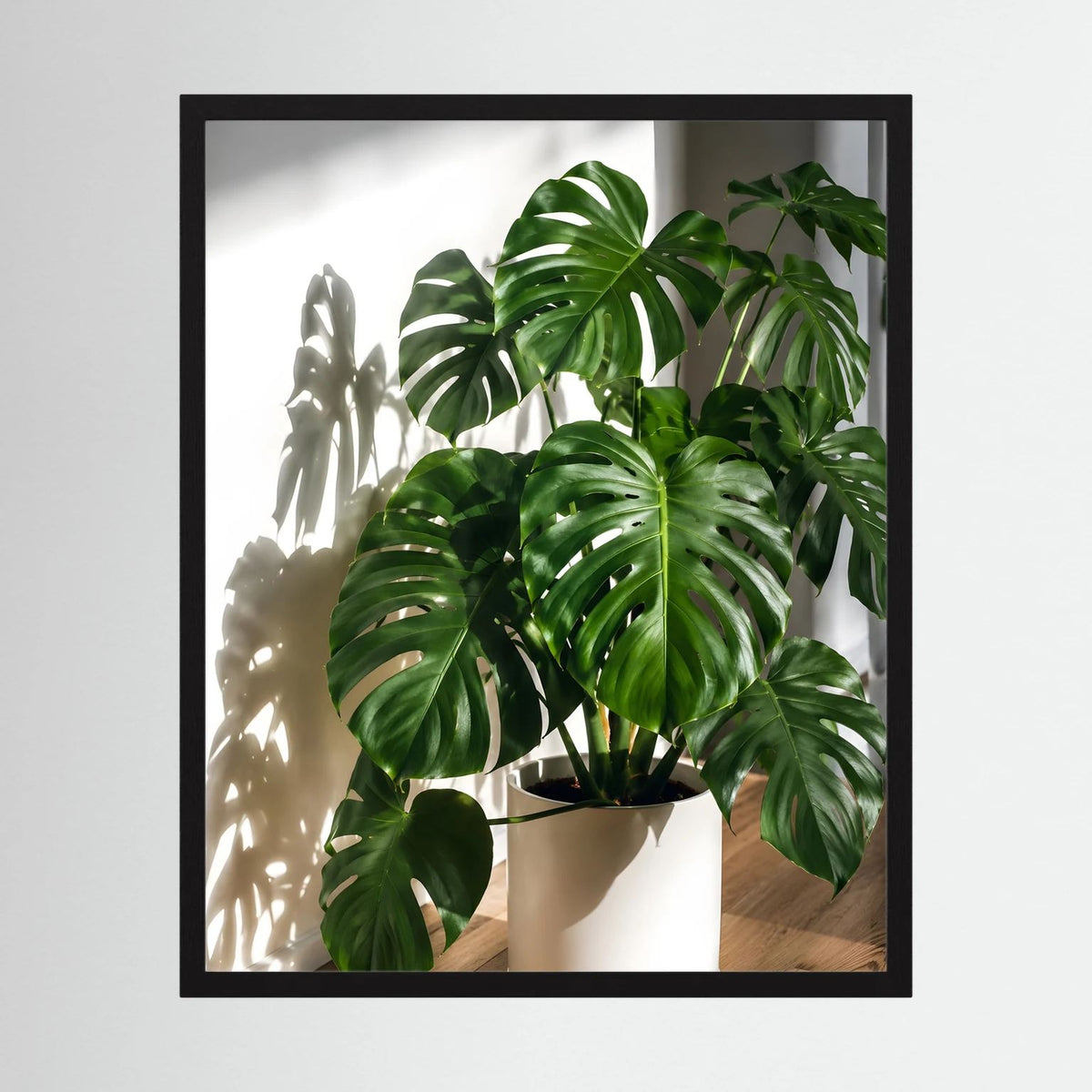 Gerahmtes Poster mit Monstera-Pflanze in hellem Topf, schwarzer Rahmen, hochformatig
