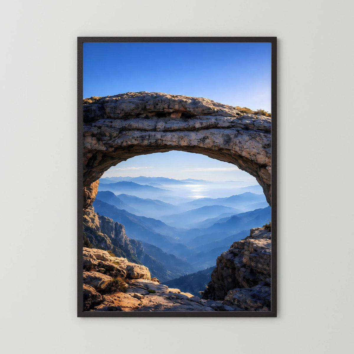 Hochformatiges Poster im schwarzen Rahmen mit Felsbogen und Blick über Berggipfel
