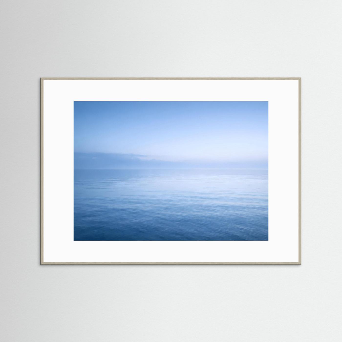 Querformatiges Wandbild mit Horizont über ruhigem Meer, beiger/grauer Rahmen.