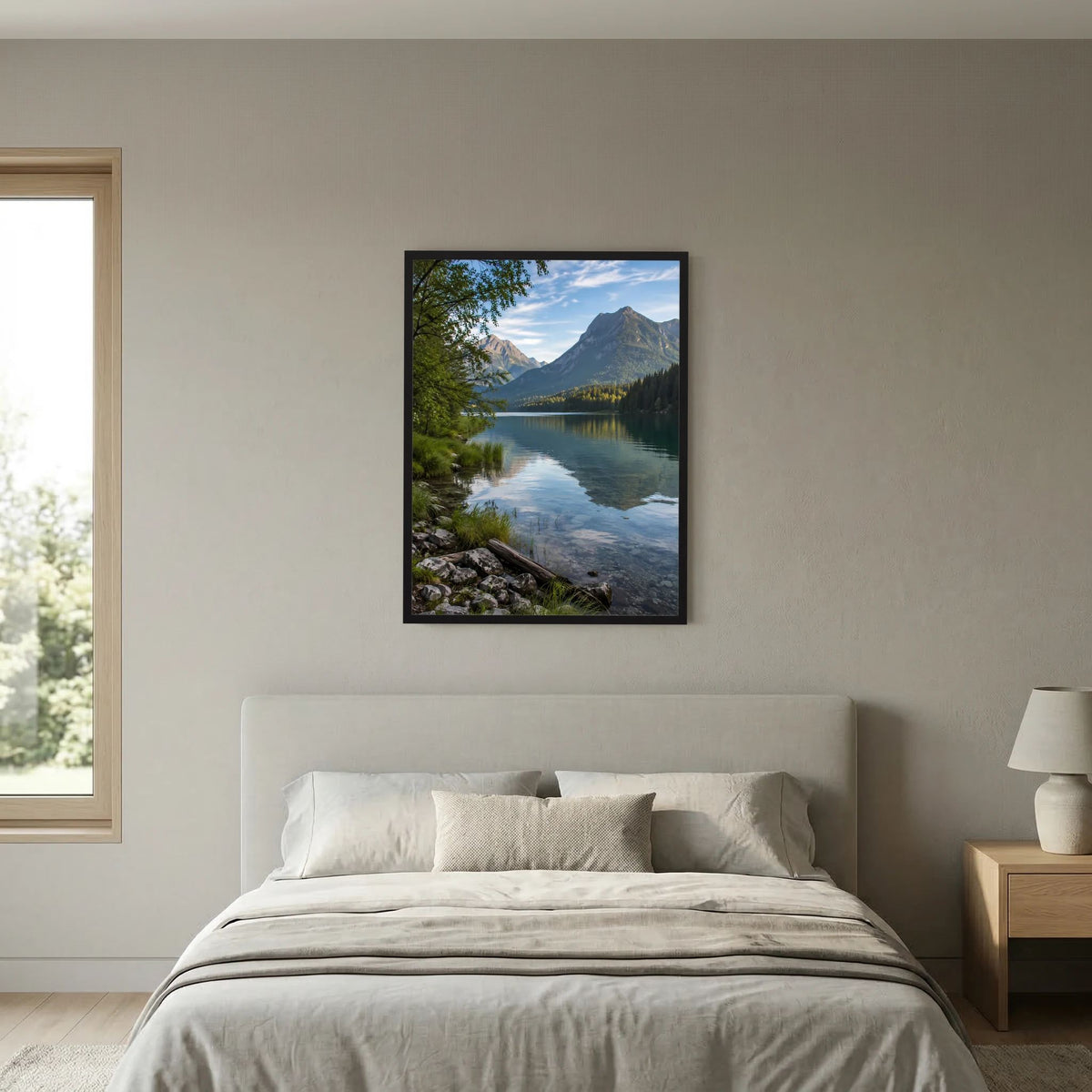 Wandposter im schwarzen Rahmen mit Alpensee und Bergen über einem weißen Bett