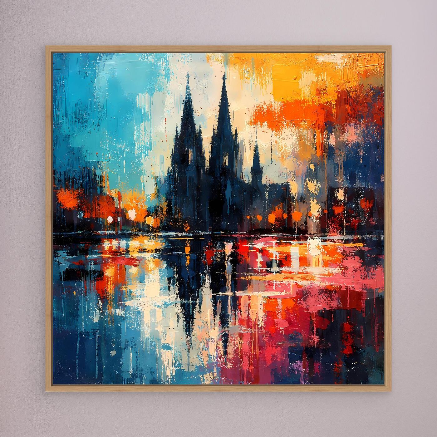 Wandbild mit hellem Holzrahmen: abstrakte Köln-Dom-Silhouette mit Spiegelung, blau-orange-rot.
