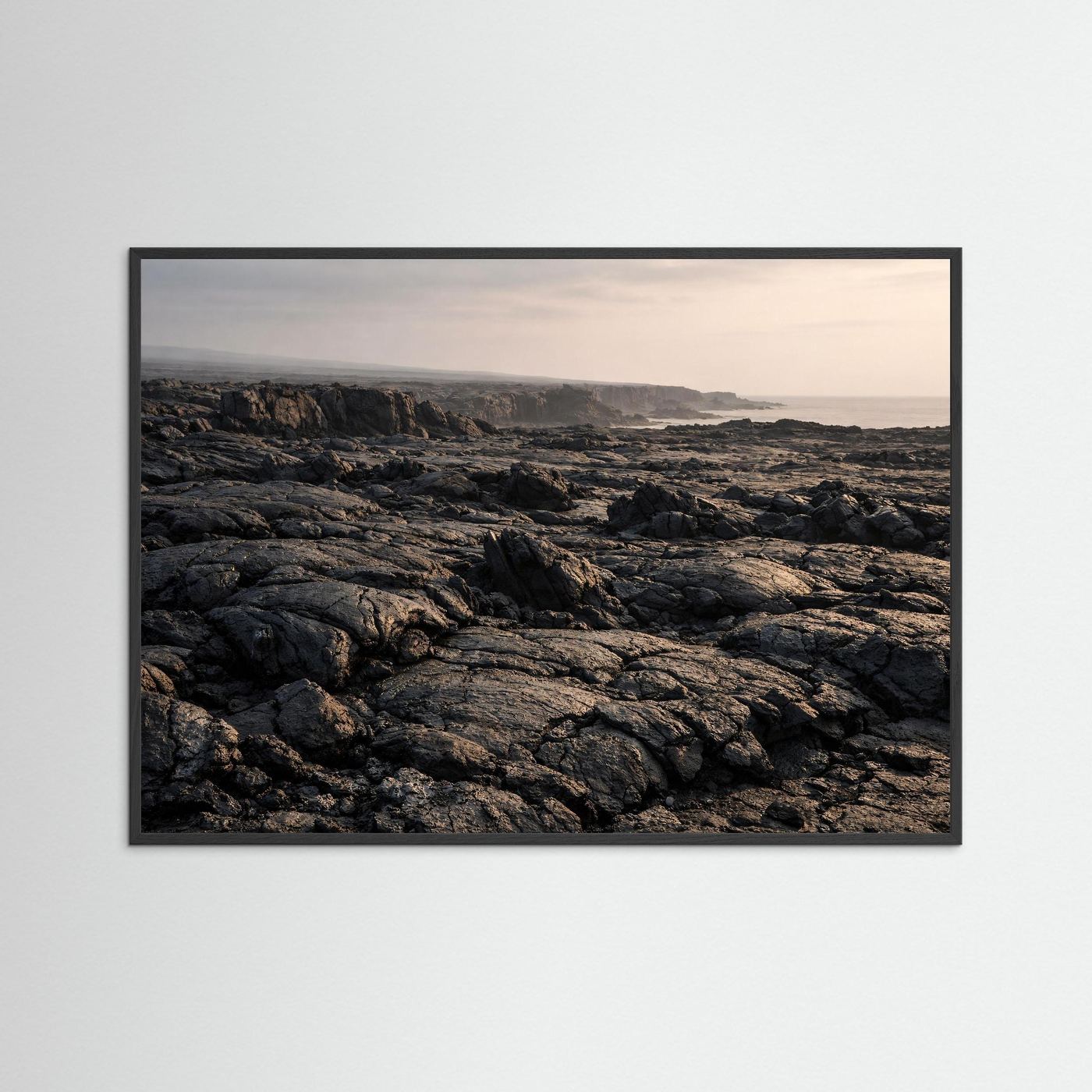Wandbild: Foto von schwarzen Lavafeldern an der Küste, schwarzer Rahmen.