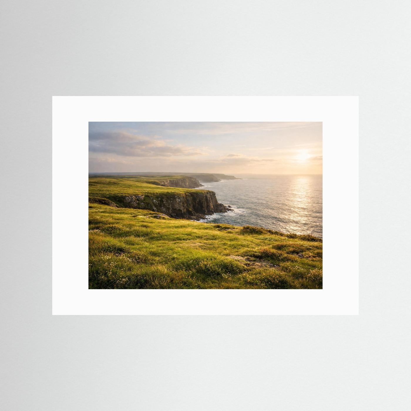 Querformat-Poster: grüne Klippen am Meer bei Sonnenuntergang, mit weißem Passepartout