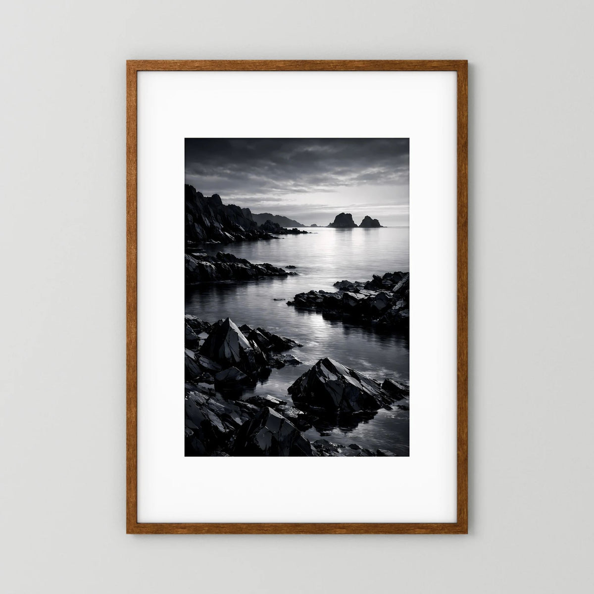 Wandbild in Schwarzweiß mit felsiger Küste und ruhigem Meer, Holzrahmen dunkelbraun