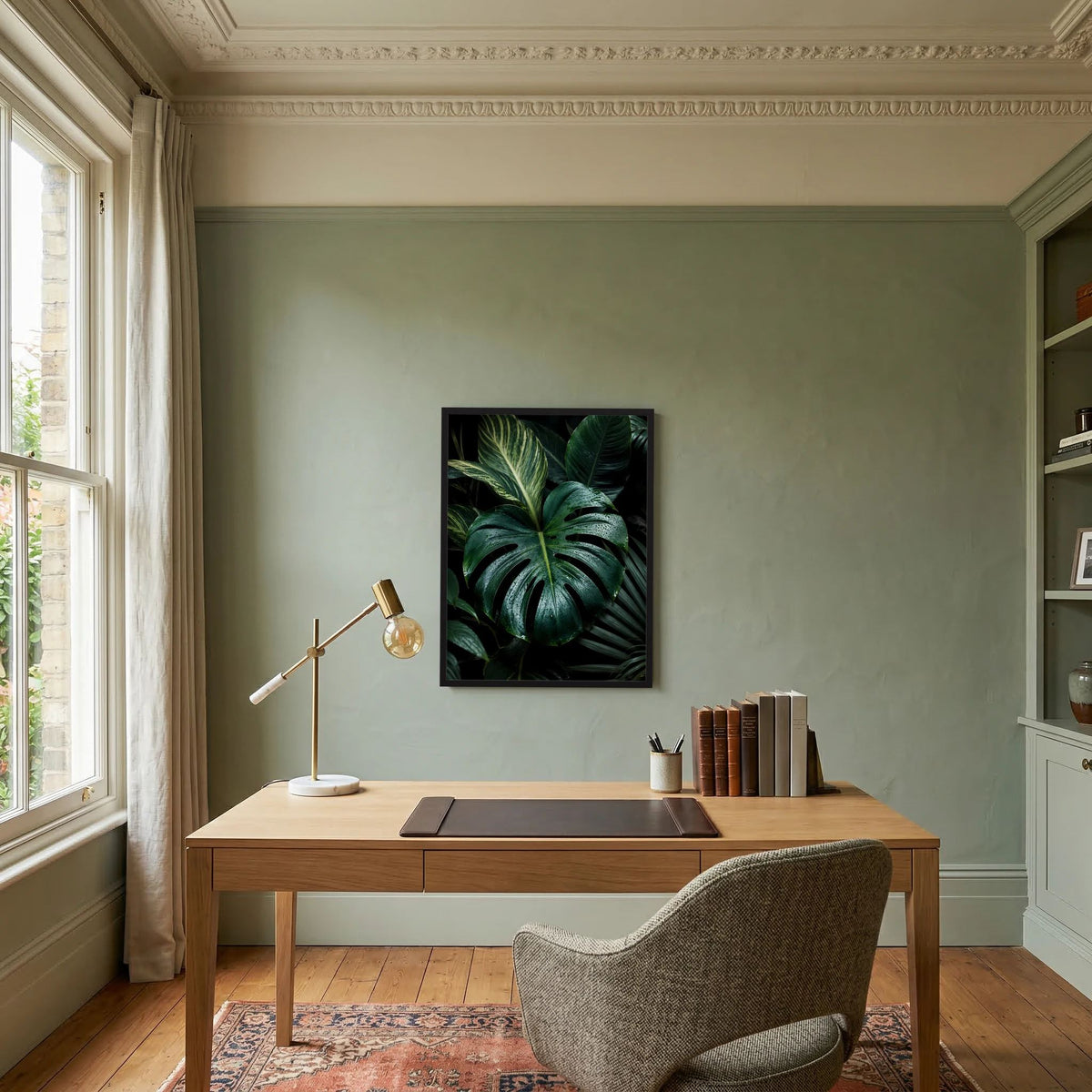 Gerahmtes Poster mit Monstera-Blättern in dunkelgrün, schwarzer Rahmen.