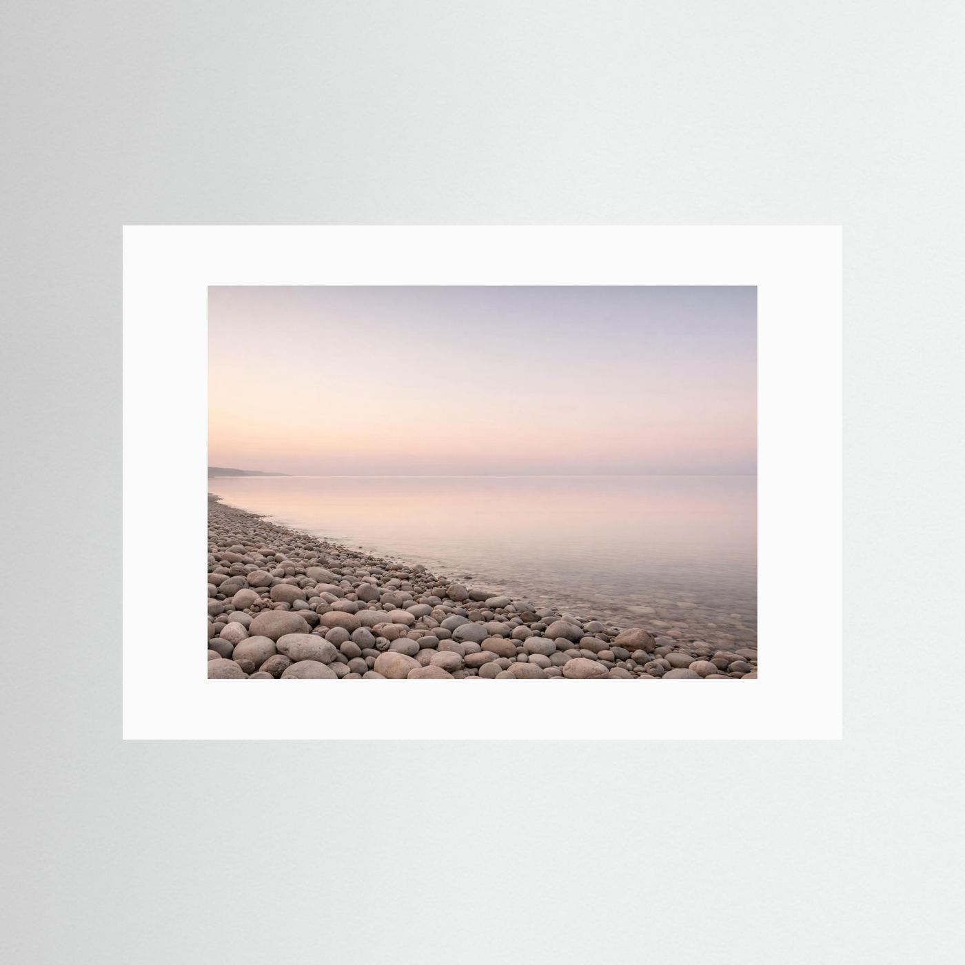 Panorama-Poster Kiesstrand und Meer im Pastelllicht, mit weißem Passepartout