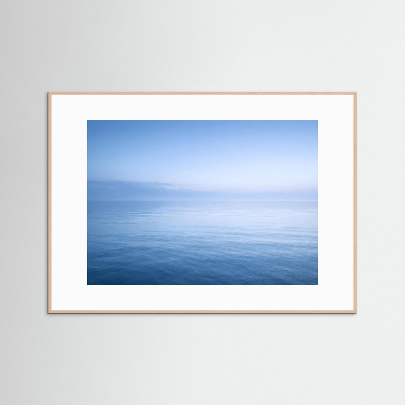 Querformatiges Wandbild mit Horizont über ruhigem Meer, heller Holzrahmen.