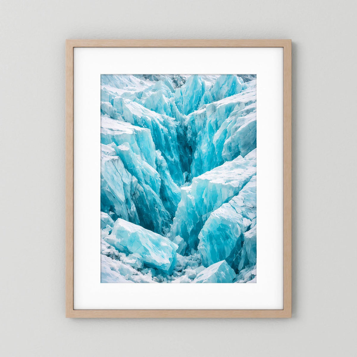 Hochformat-Poster mit Eislandschaft in Blau- und Weißtönen, im hellbraunen Holzrahmen