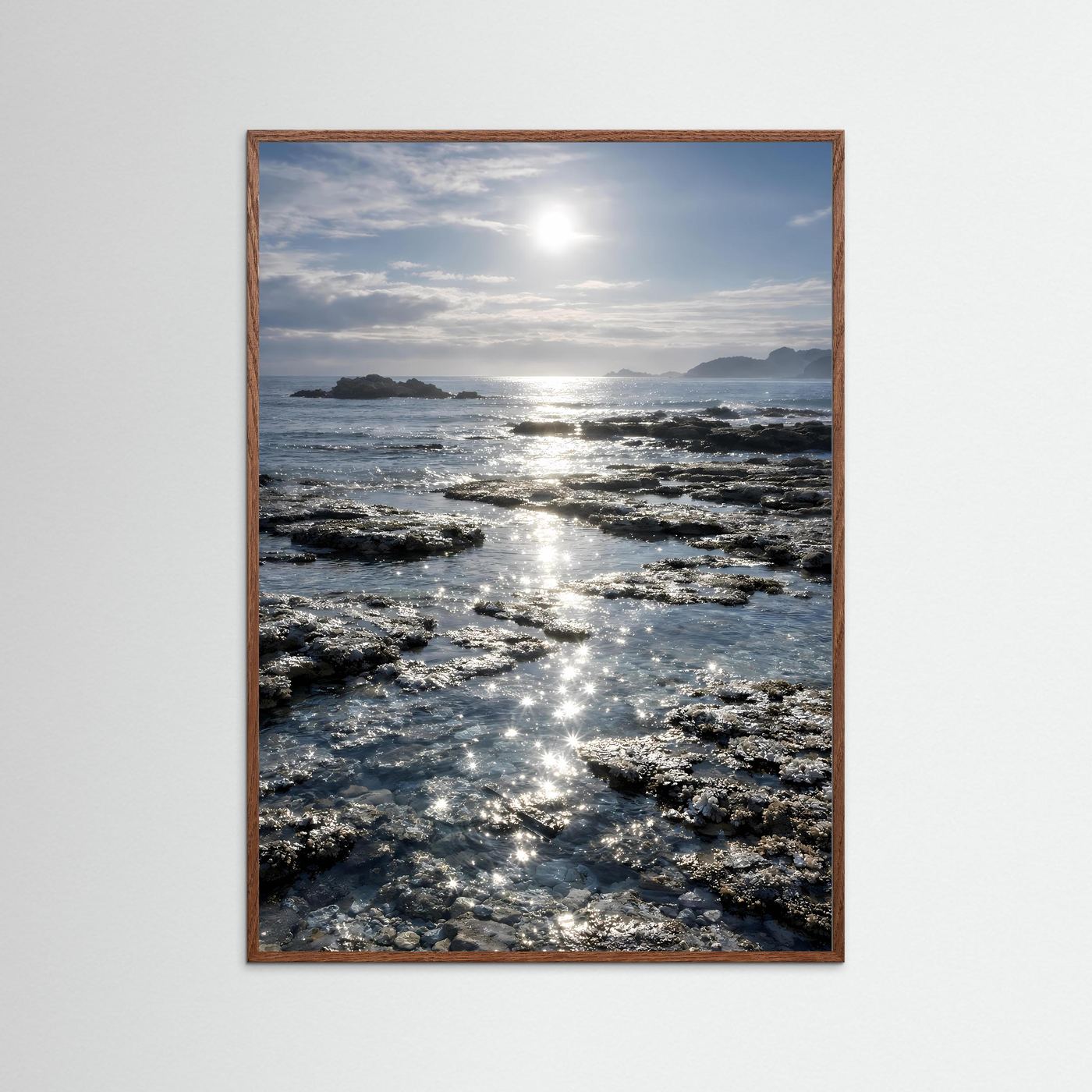 Küstenposter im Hochformat mit braunem Holzrahmen, Felsen und glitzerndem Meereslicht