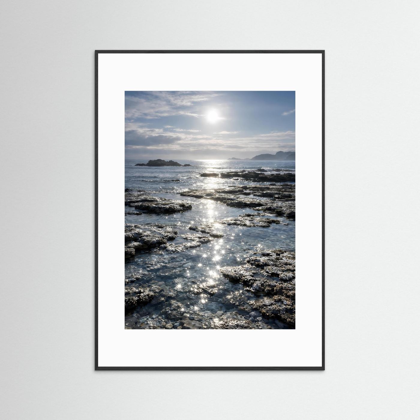 Küstenposter im Hochformat mit schwarzem Rahmen und weißem Rand, Felsen & Sonnenreflexe