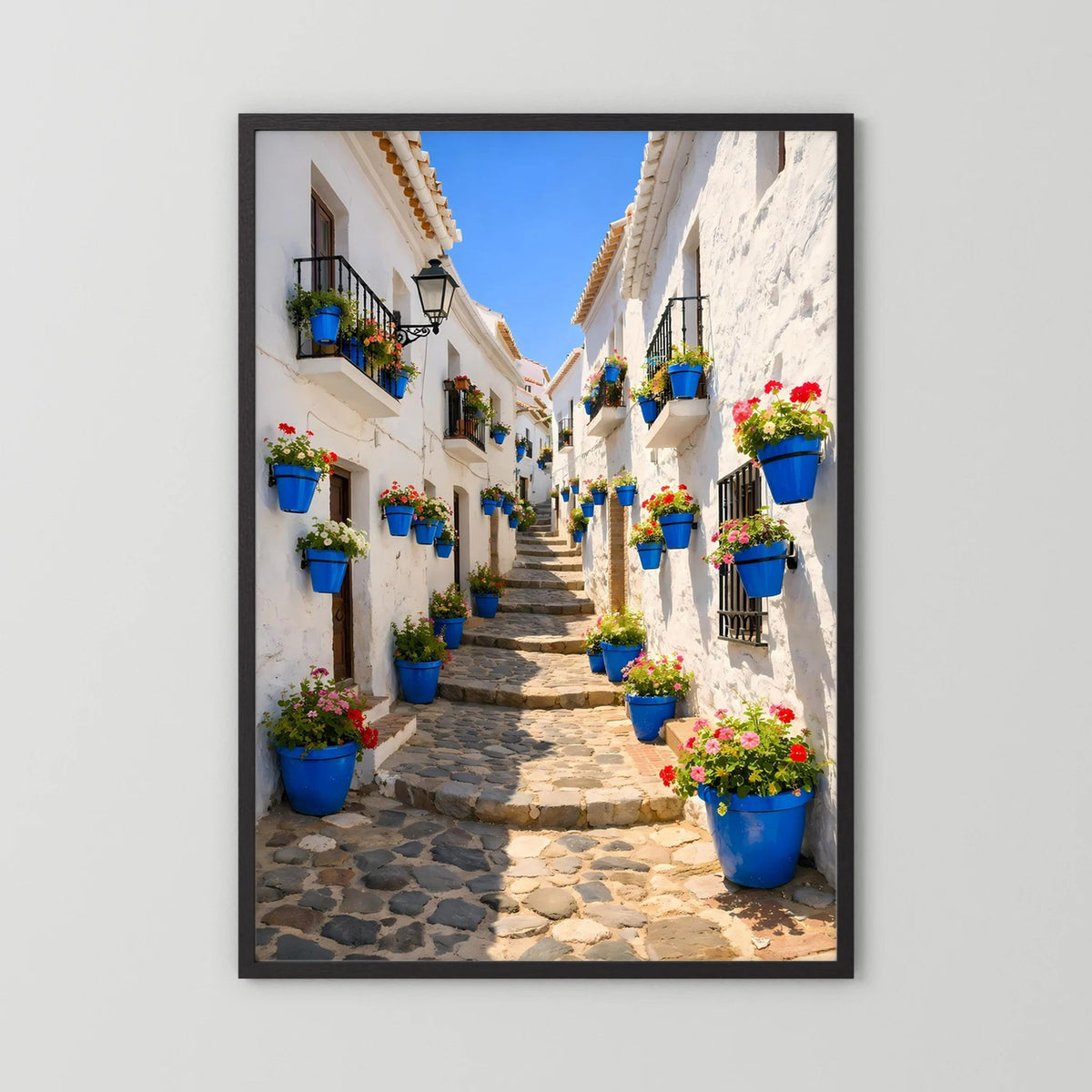 Hochformatiges Wandbild mit schwarzem Rahmen: Gasse mit blauen Blumentöpfen