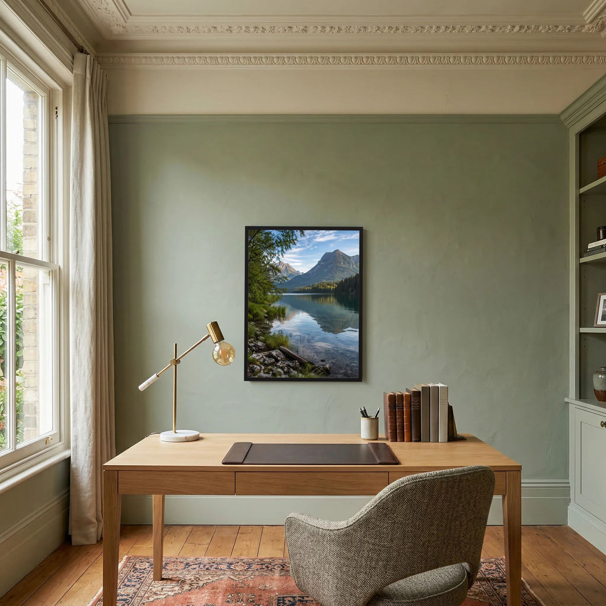 Wandposter mit Alpensee und Bergen im schwarzen Rahmen über einem Schreibtisch