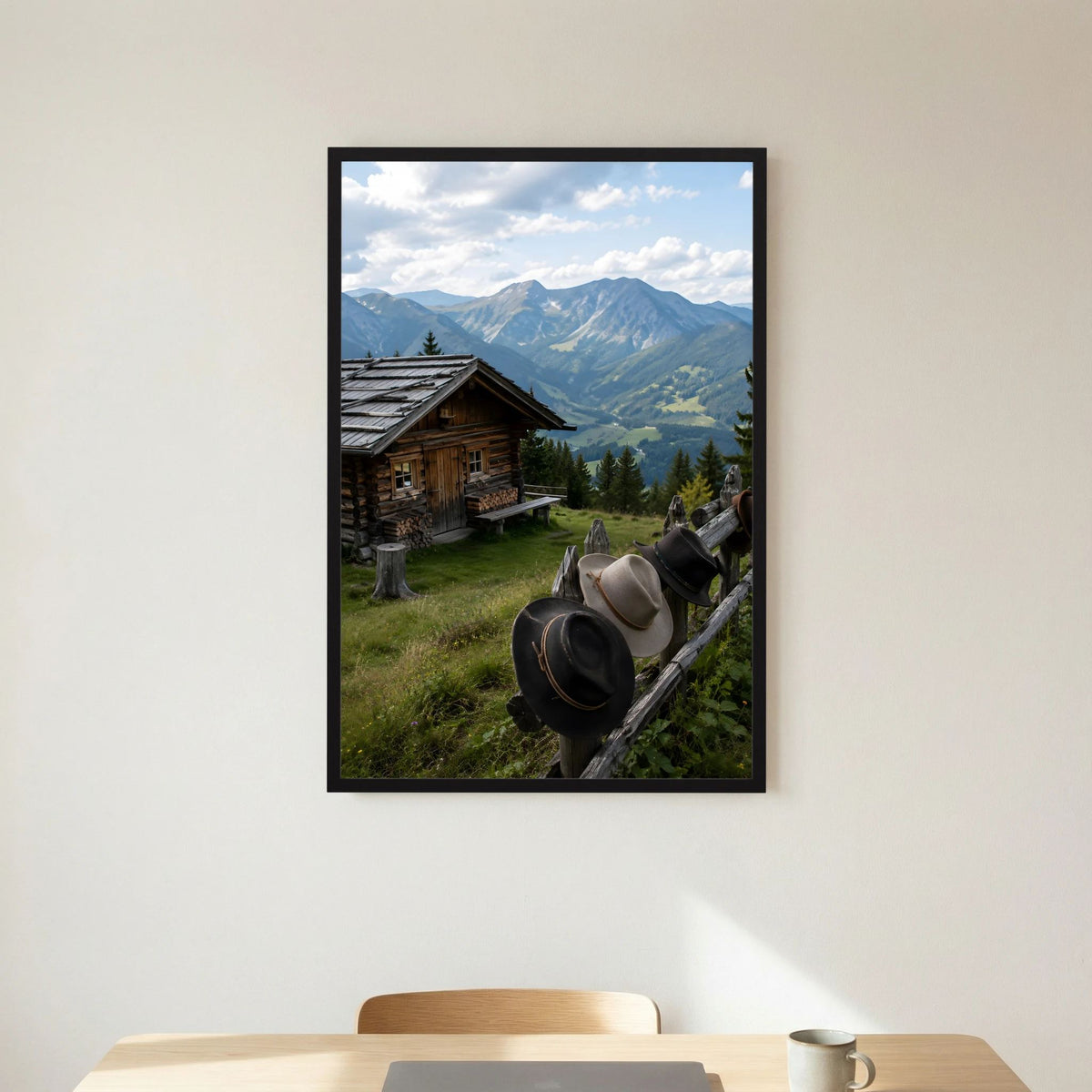 Hochformatiges Landschaftsposter mit Almhütte, Bergpanorama und Hüten am Zaun, schwarz gerahmt