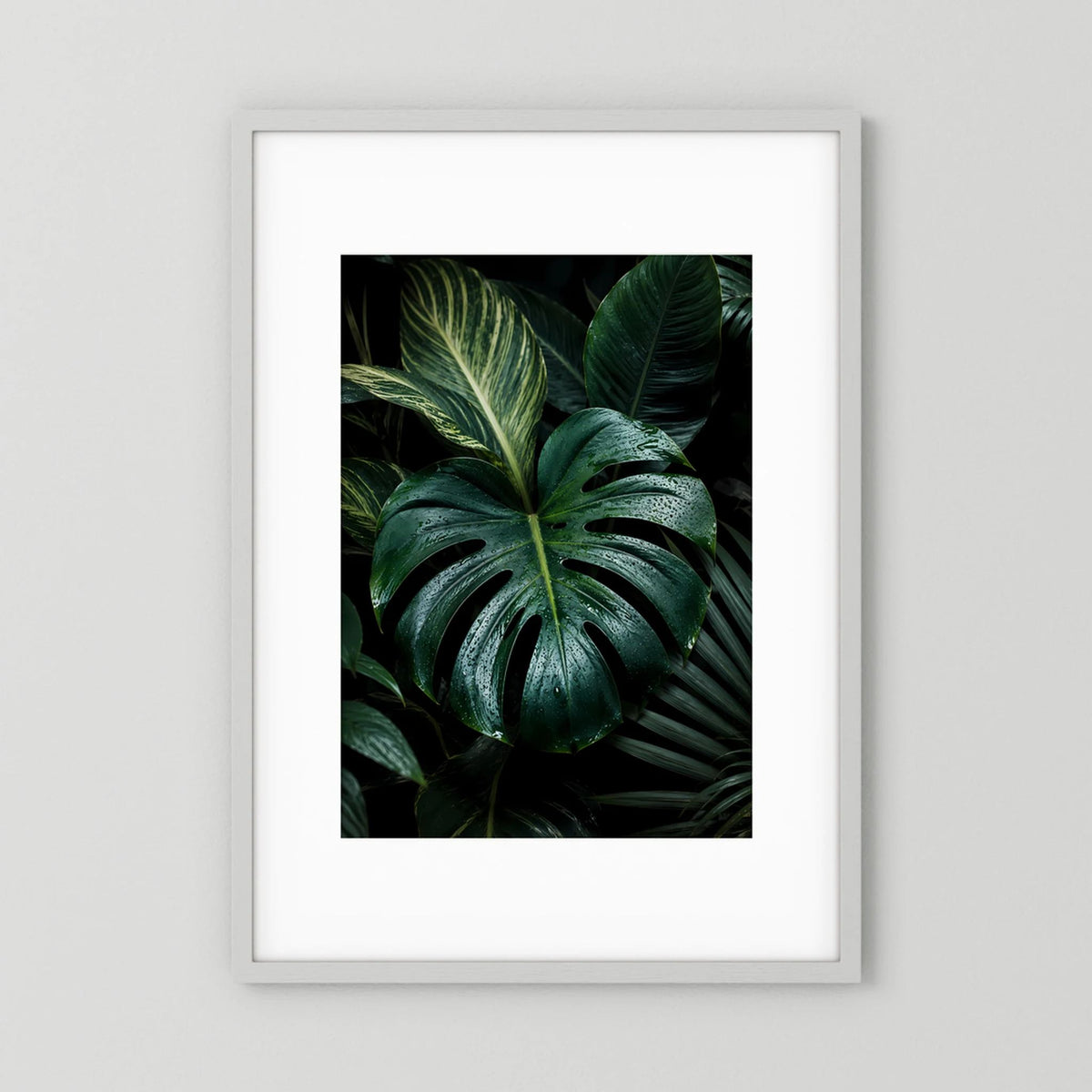 Gerahmtes Poster mit Monstera-Blättern in dunkelgrün, weiße Rahmenfassung.
