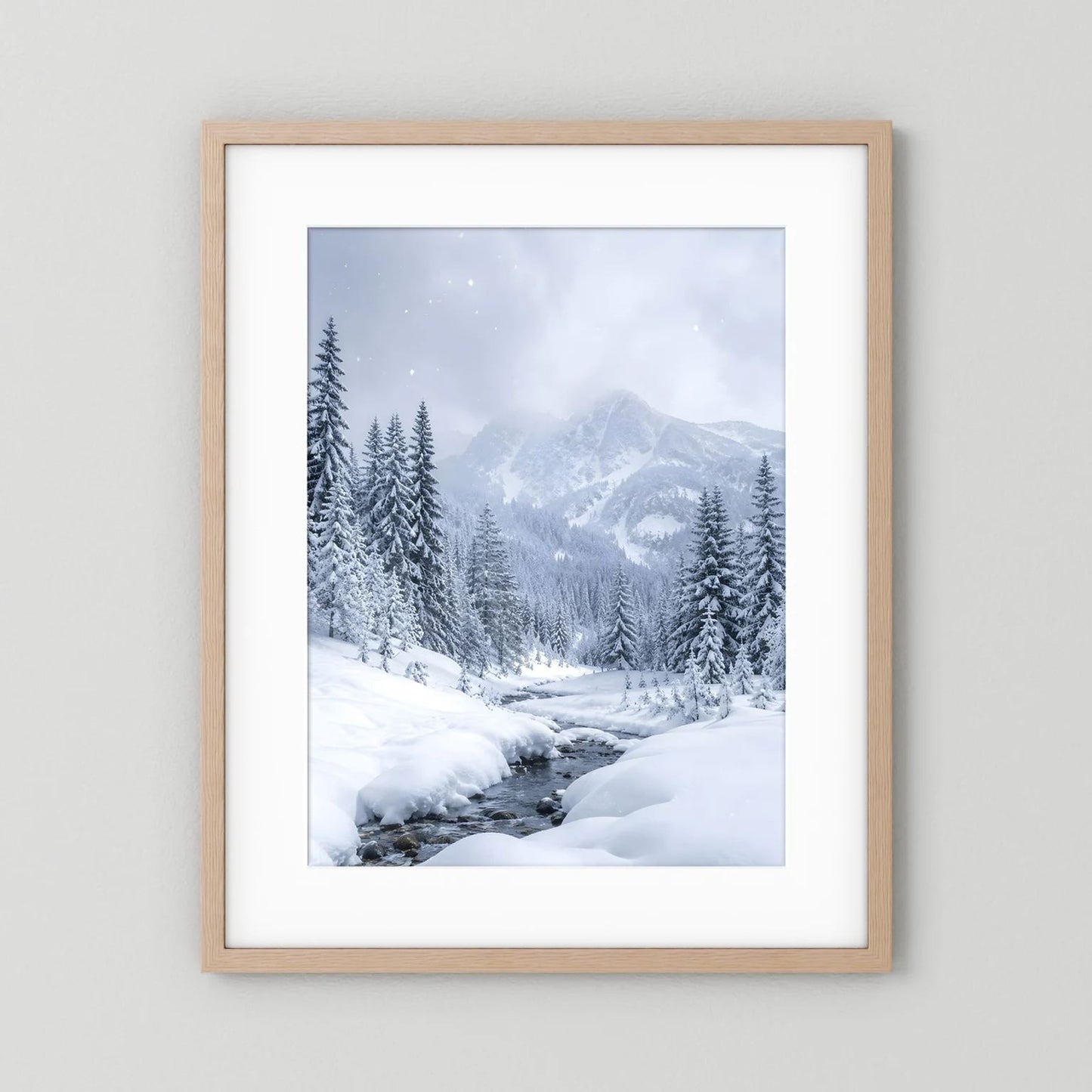 Winterlandschaft-Wandbild mit hellem Holzrahmen und weißem Passepartout: verschneite Berge und Tannen.