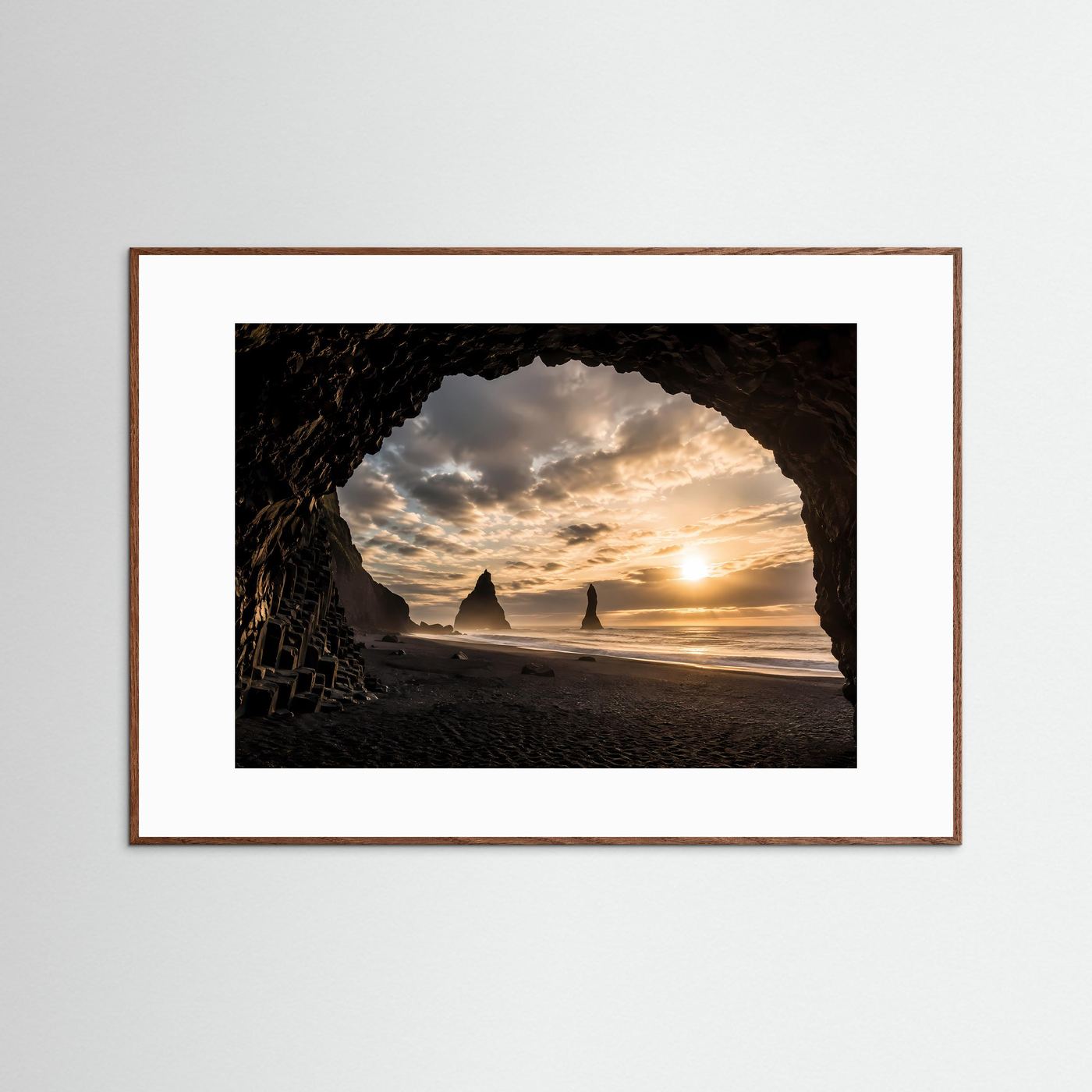 Querformatiges Poster: Felsbogen am schwarzen Sandstrand im Sonnenuntergang, braun gerahmt